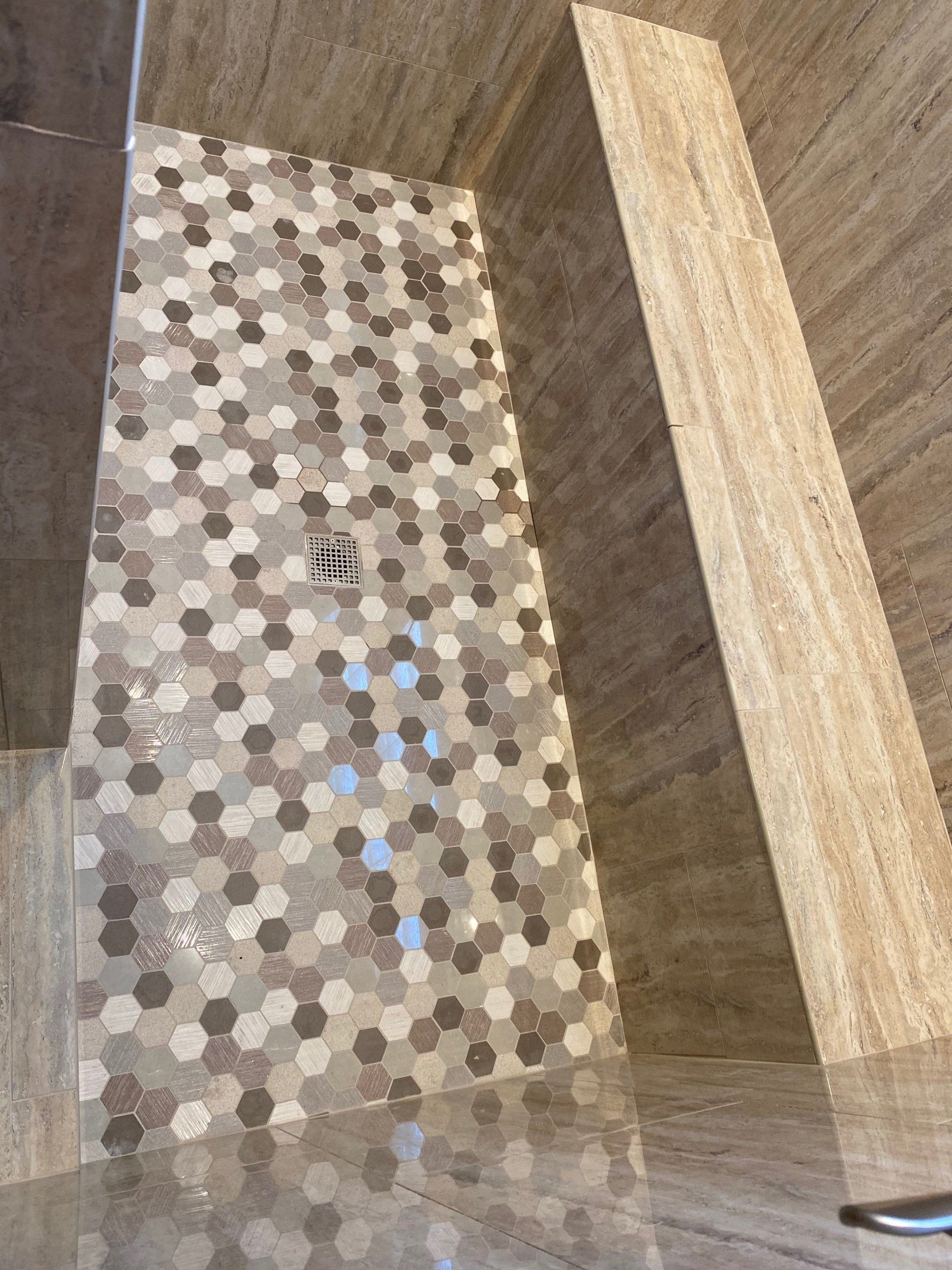 A shower with a tiled floor and a drain