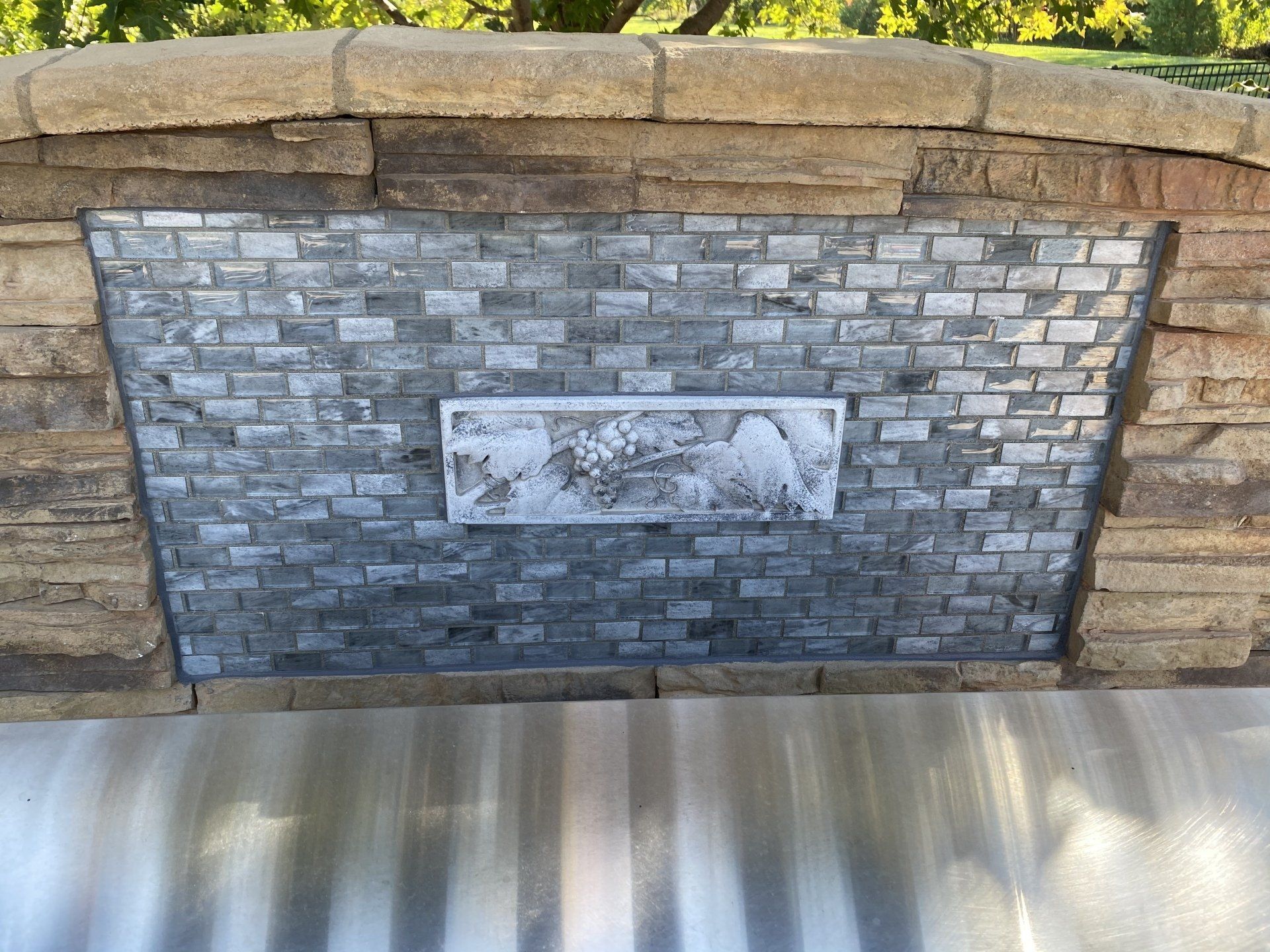 A brick wall with a stainless steel hood behind it.