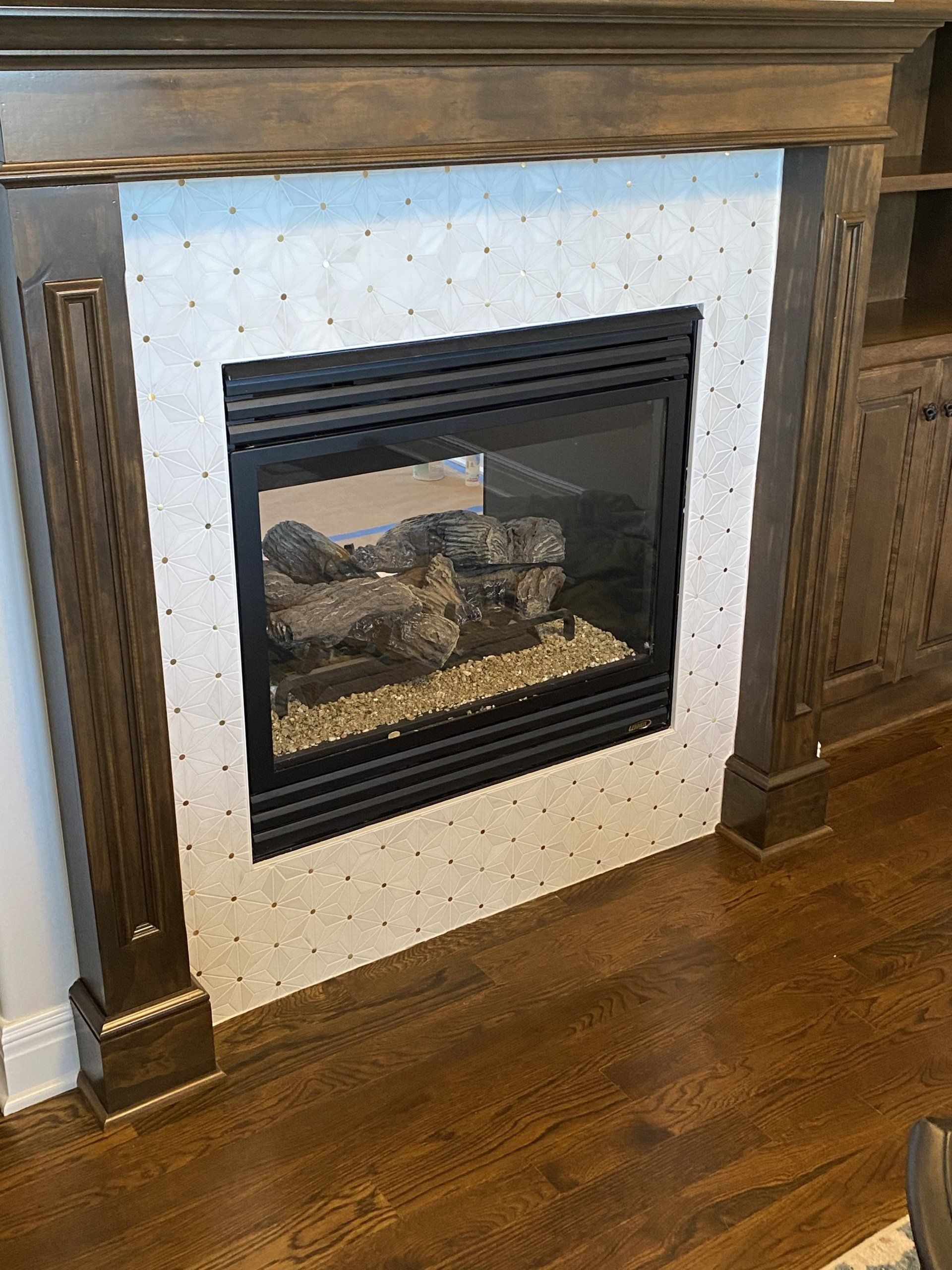 A fireplace with a wooden mantle and a wooden floor in a living room.
