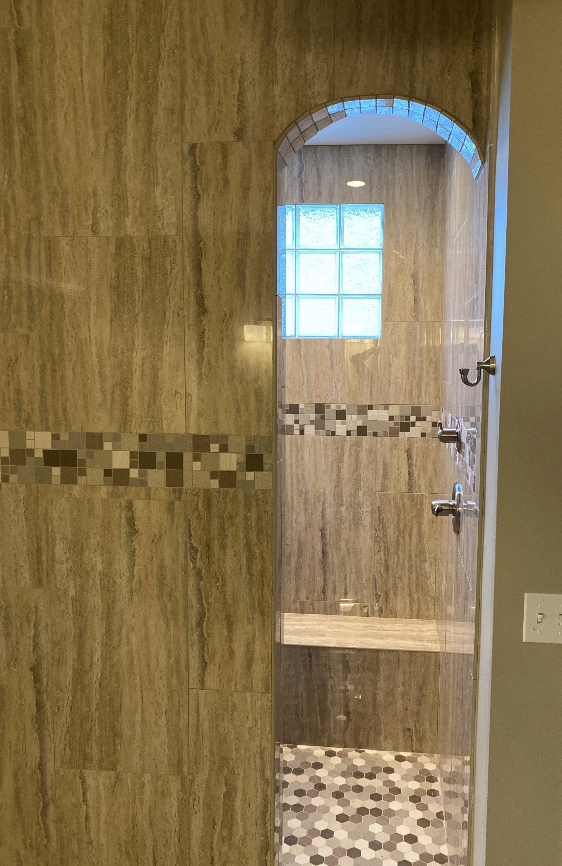 A bathroom with a walk in shower and a window.
