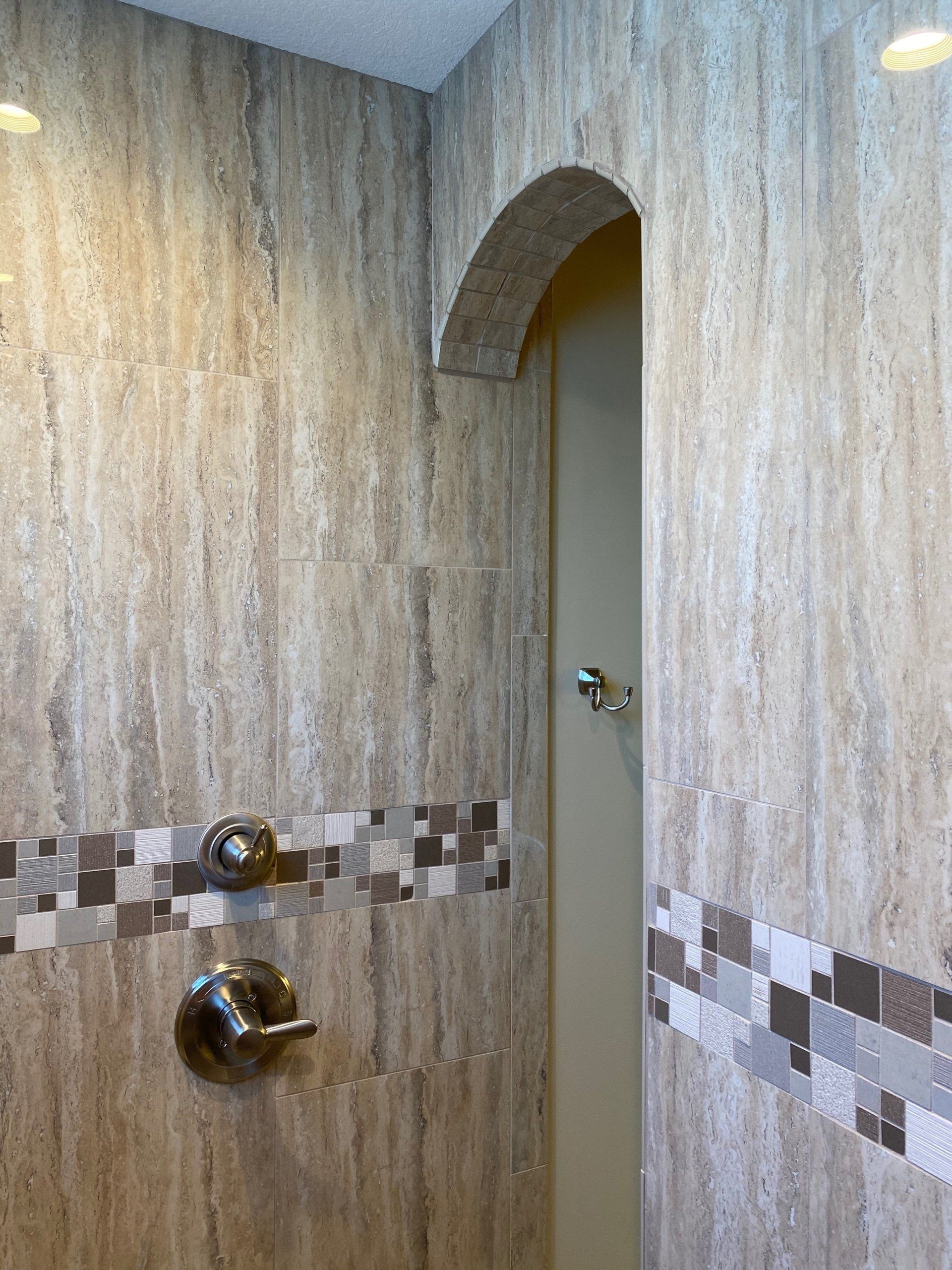 A bathroom with a walk in shower and a tiled wall.