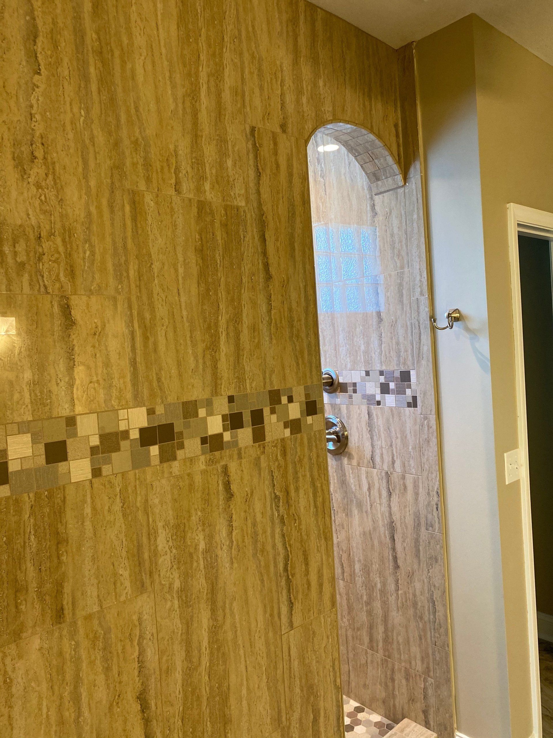 A bathroom with a walk in shower and a tiled wall.