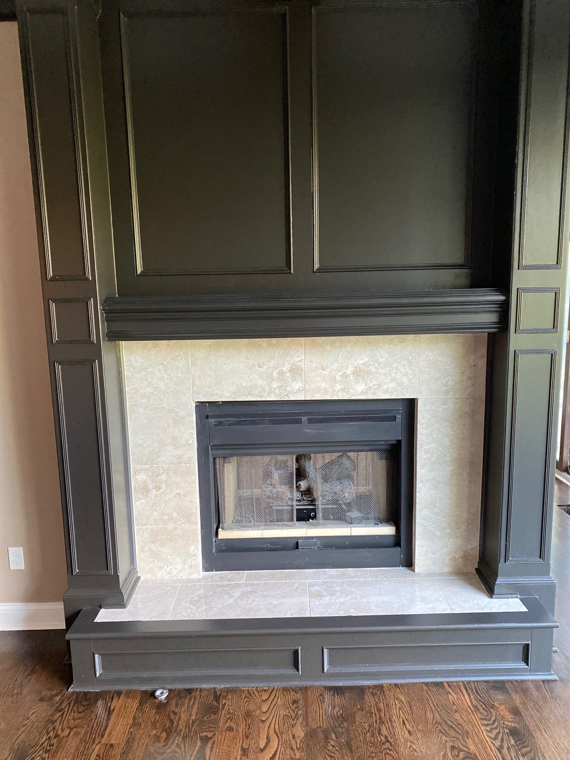 A fireplace with a black mantle in a living room.
