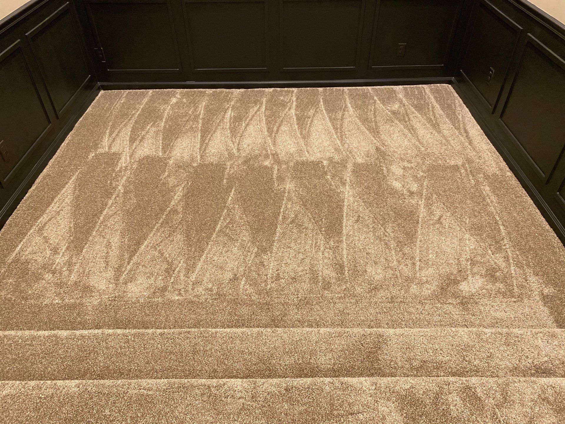 A close up of a carpeted floor with stairs in a room.
