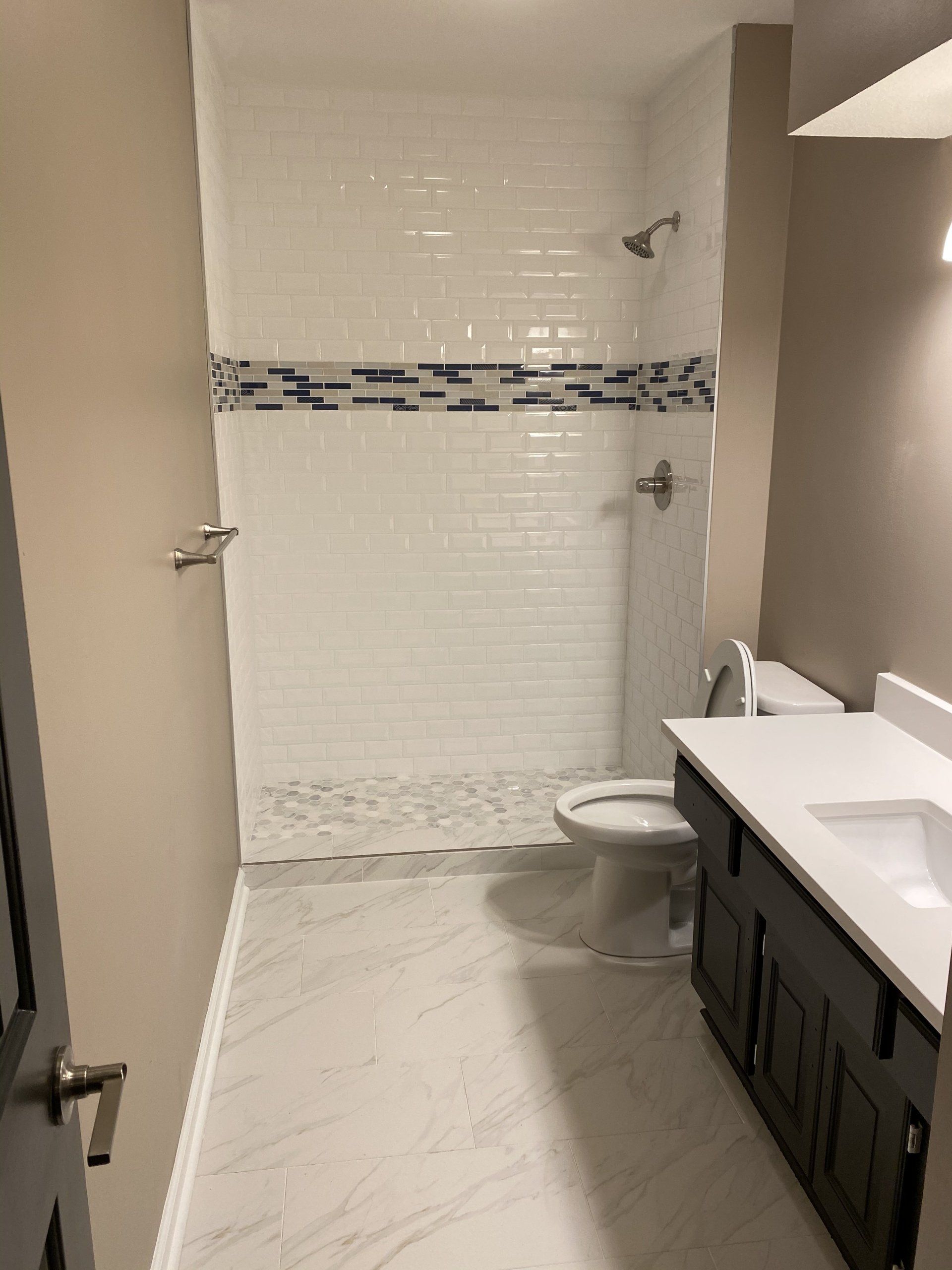 A bathroom with a toilet , sink and shower.