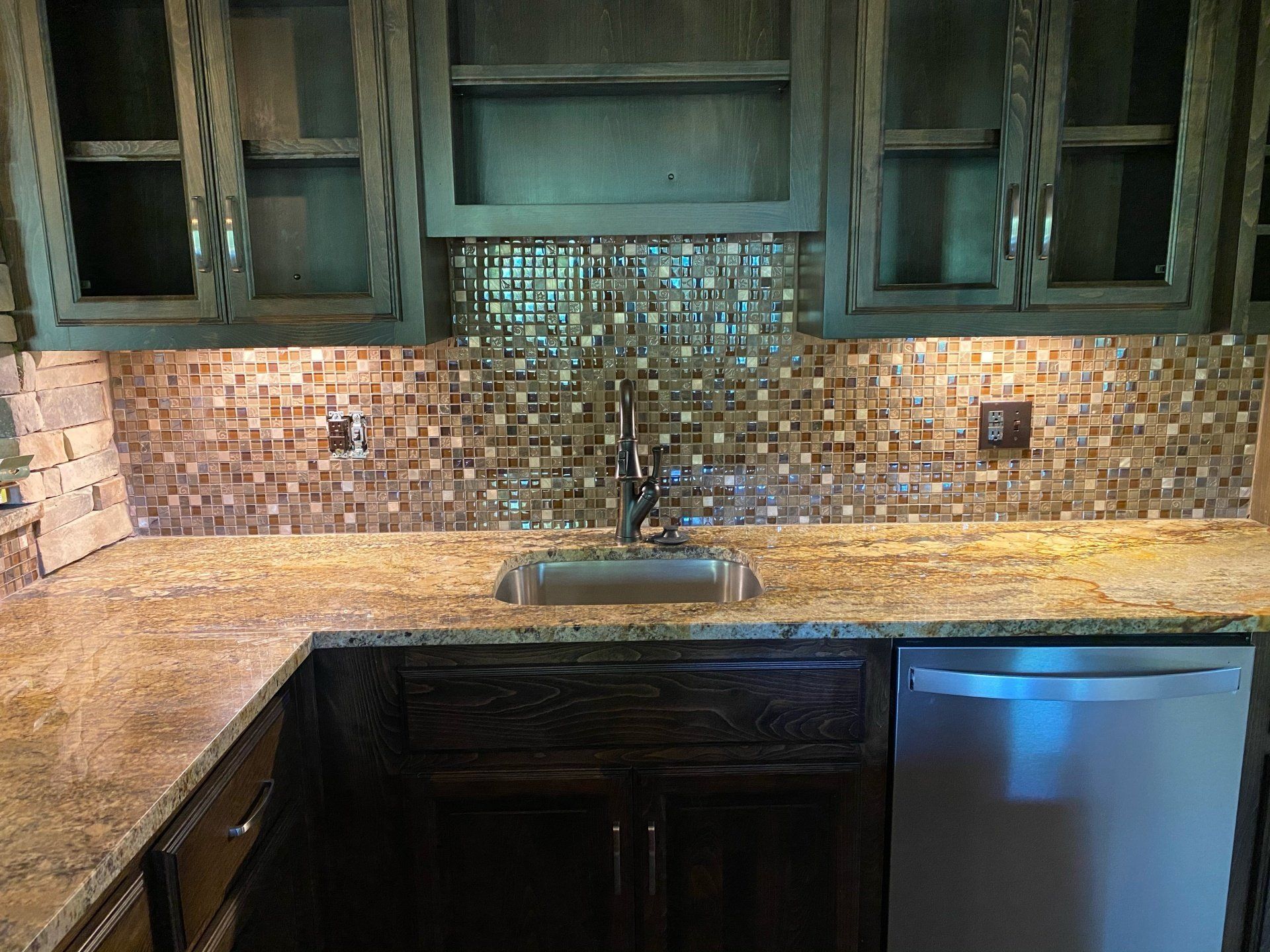 A kitchen with a sink , cabinets , and a stainless steel dishwasher.