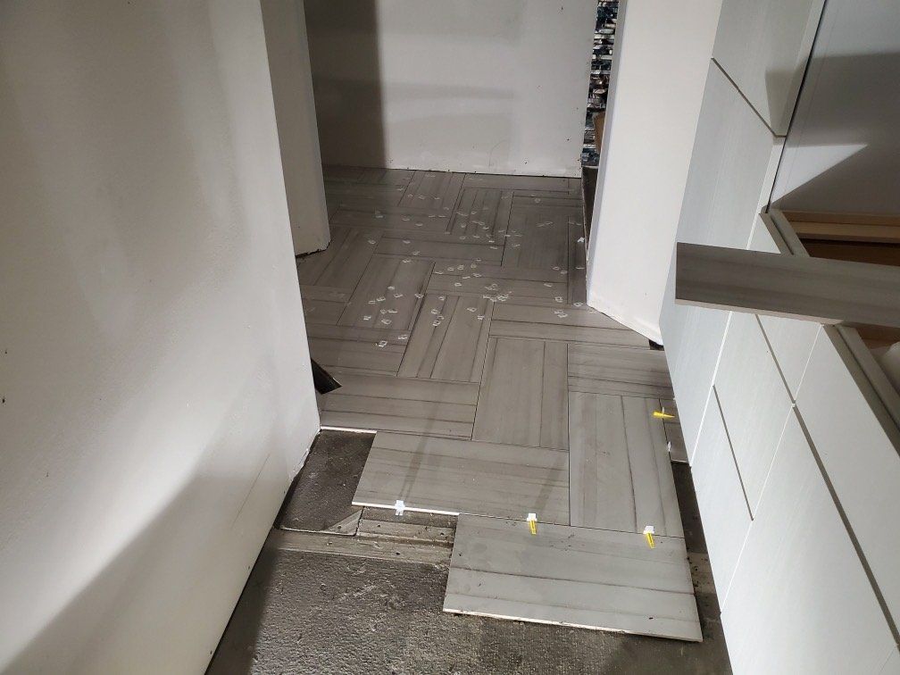 A room with a broken tile floor and a broken door.