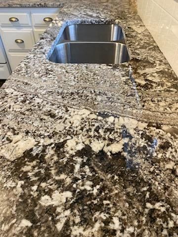 A kitchen sink is sitting on top of a granite counter top.