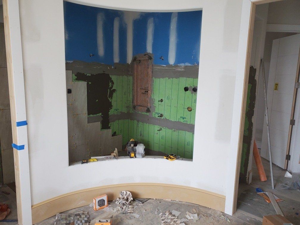 A bathroom under construction with a curved wall and green tiles.