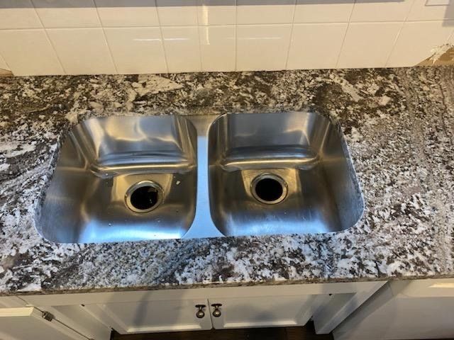 A stainless steel kitchen sink on a granite counter top