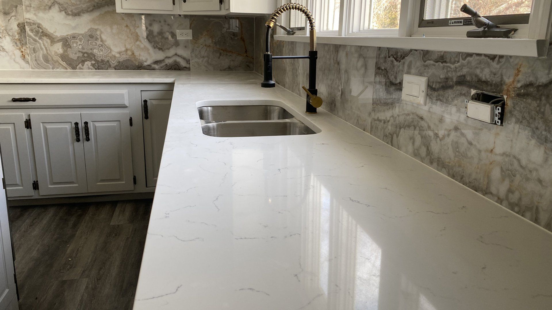 A kitchen with white cabinets , a sink , and a window.