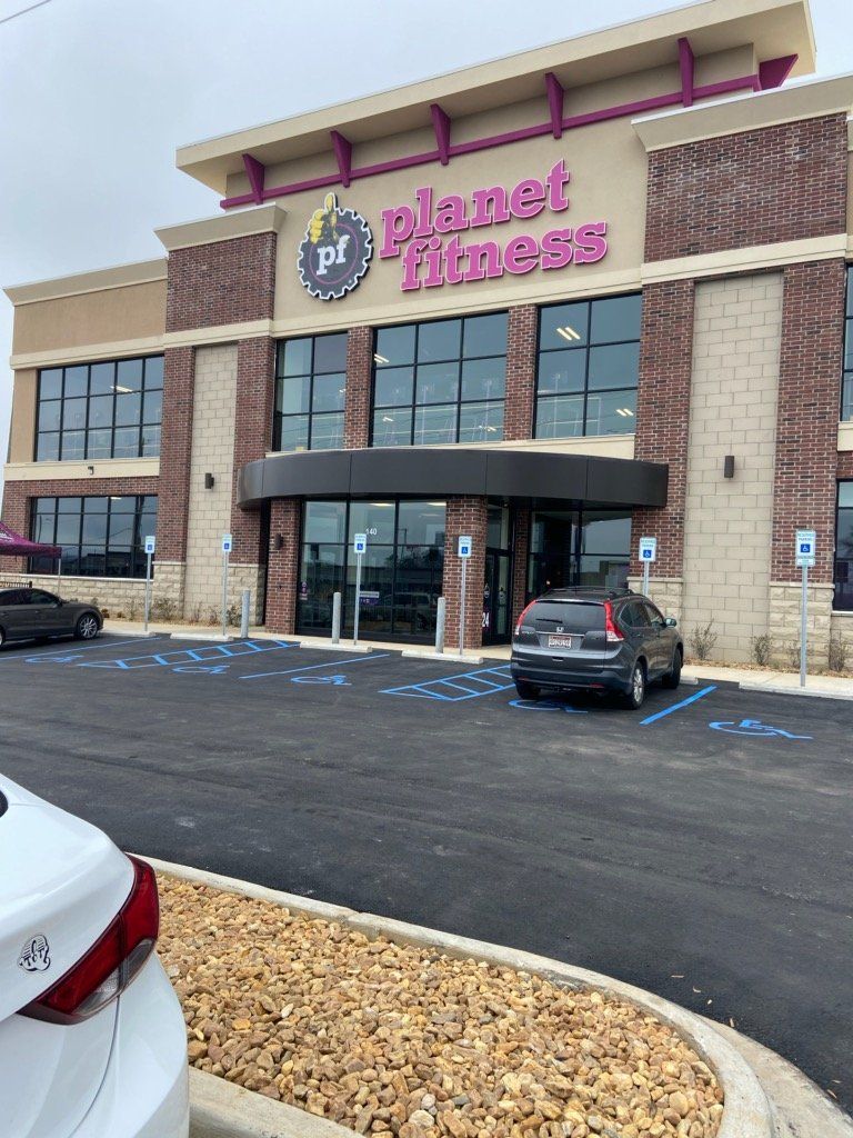 A car is parked in front of a planet fitness gym.