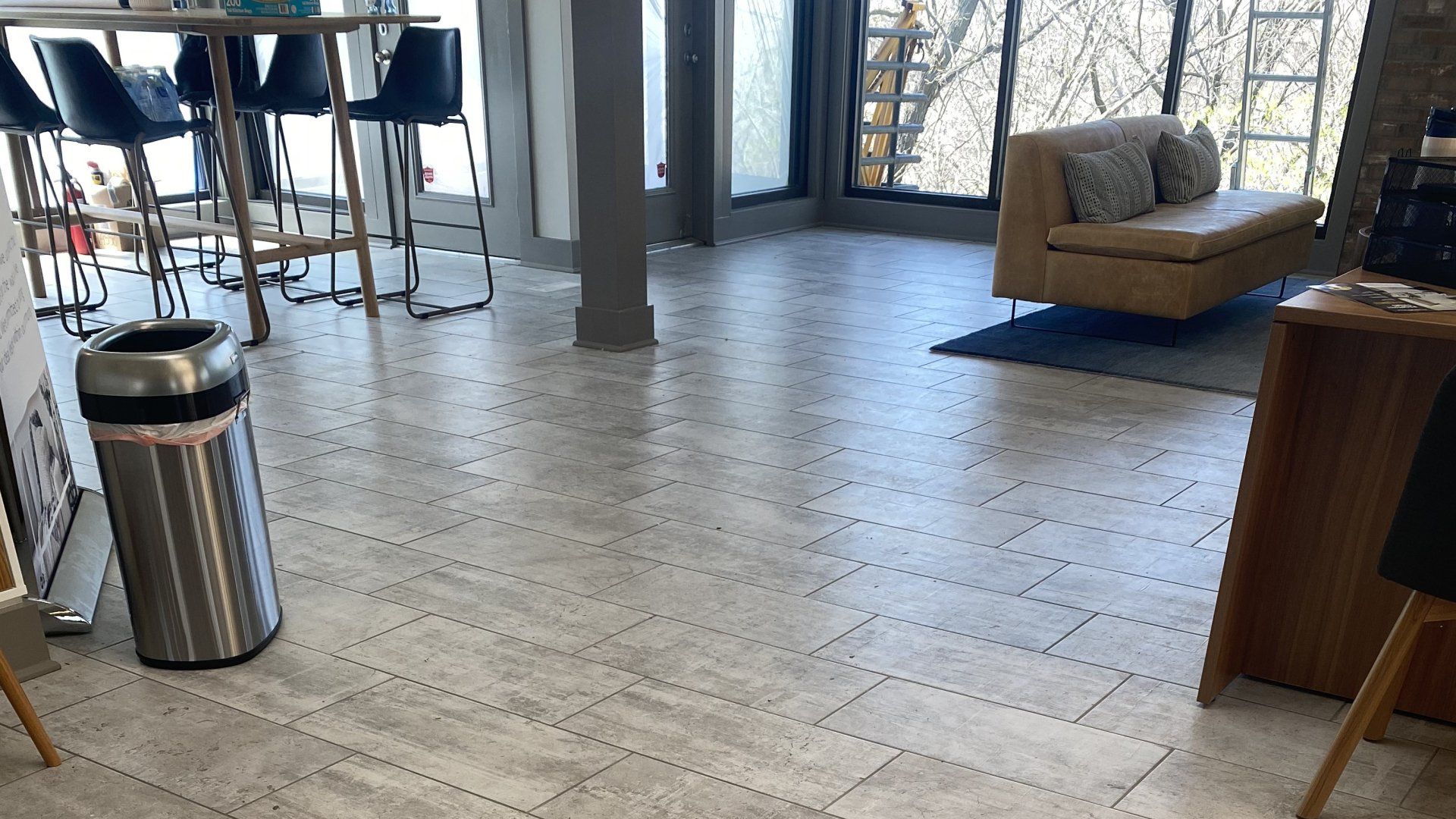 A room with a couch and a trash can on the floor