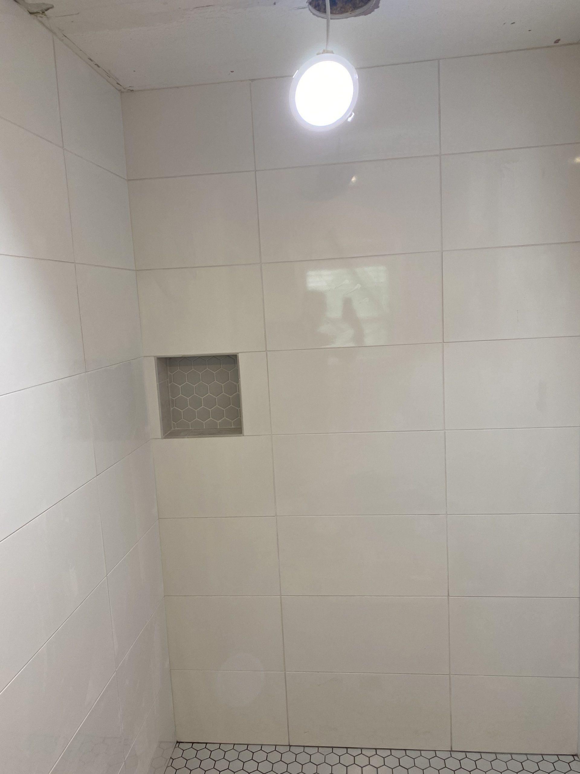 There is a light hanging from the ceiling in the shower.