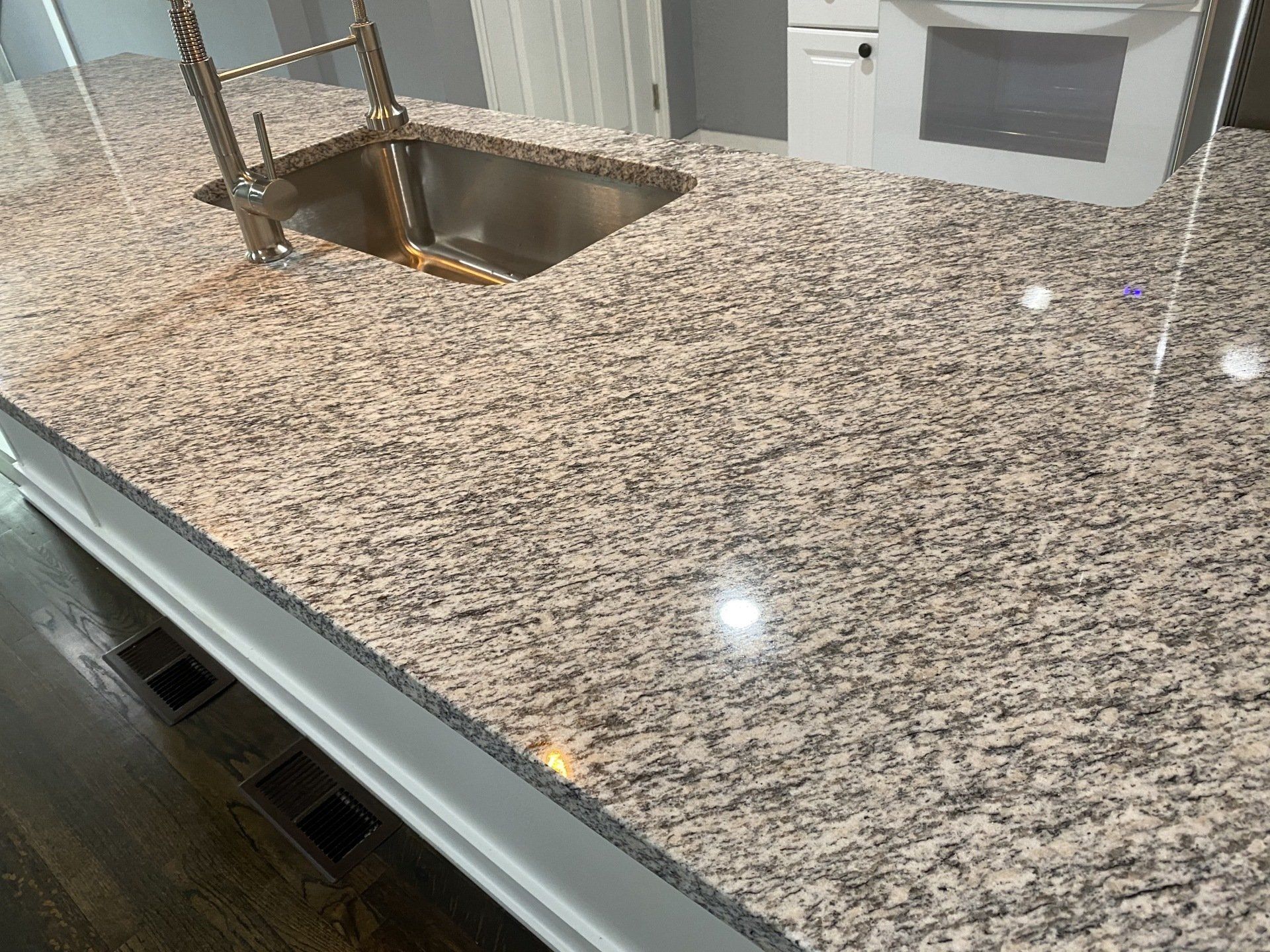 A kitchen with granite counter tops and a stainless steel sink.