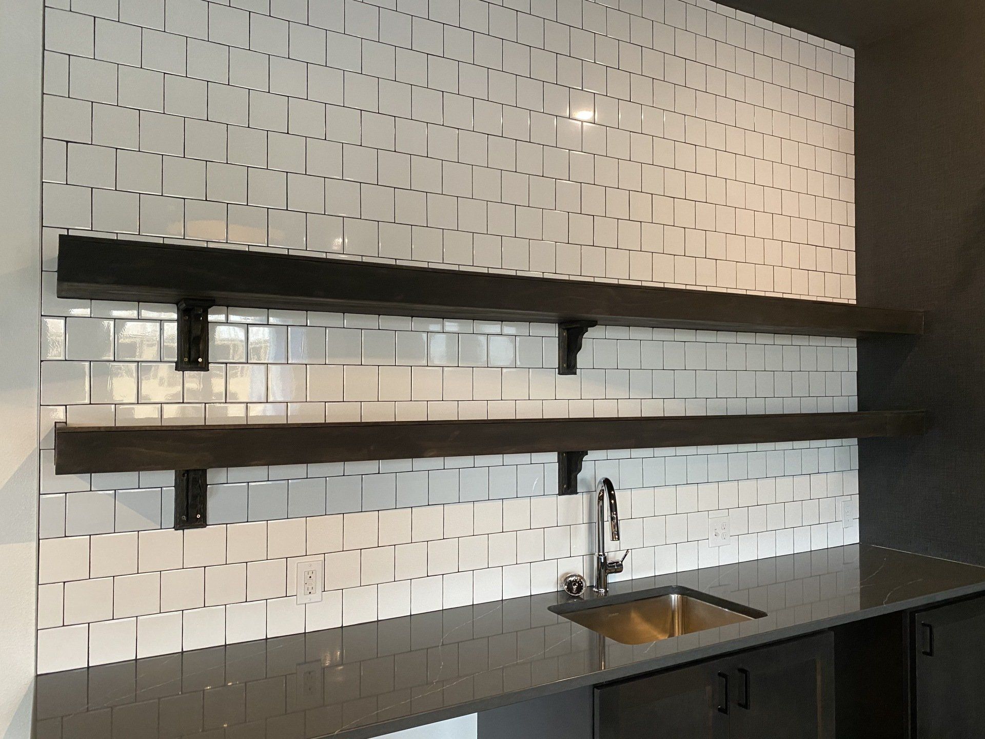 A kitchen with a sink and shelves on the wall