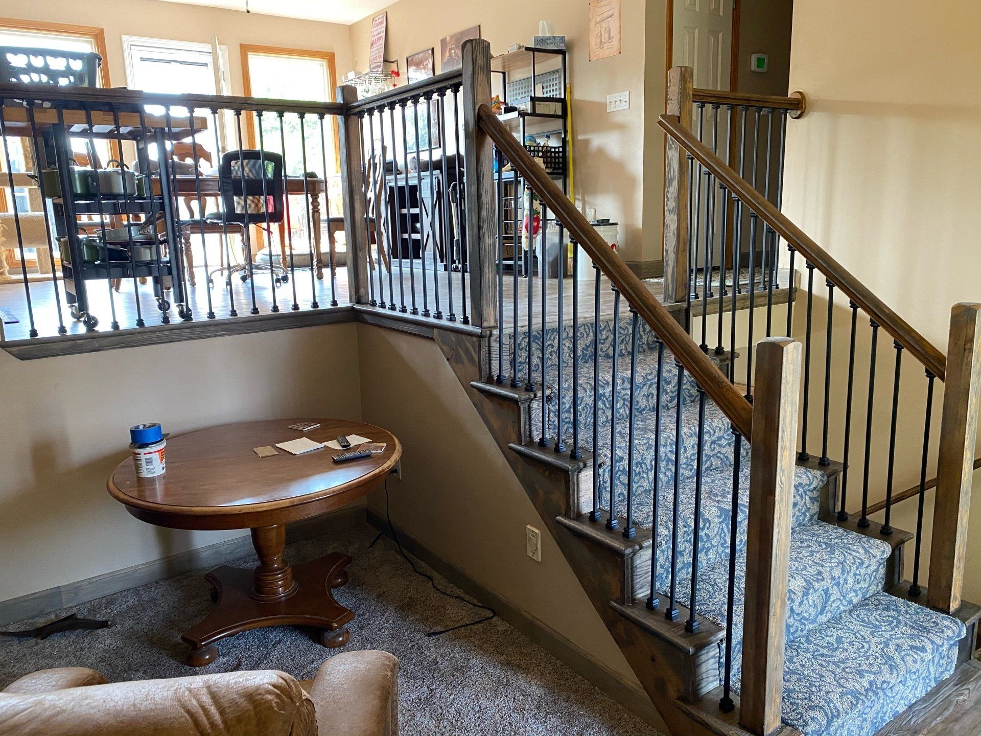 A living room with stairs leading up to the second floor and a table.
