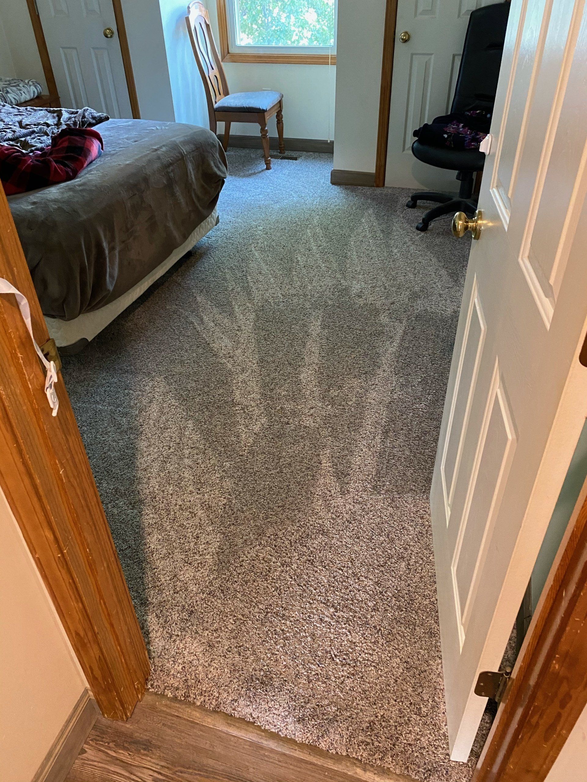 A bedroom with a bed , chair , and carpeted floor.