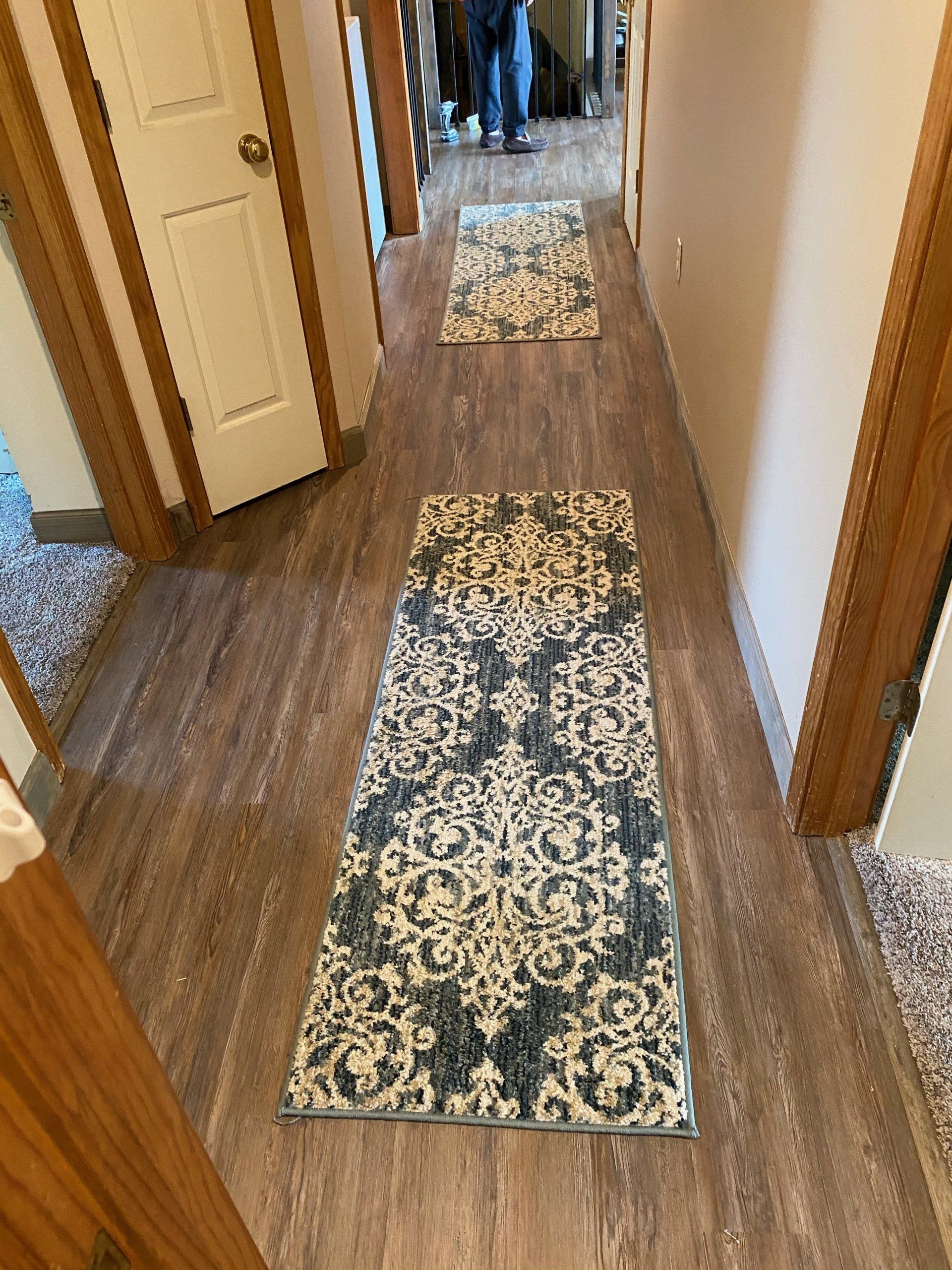 A hallway with hardwood floors and a rug on the floor.