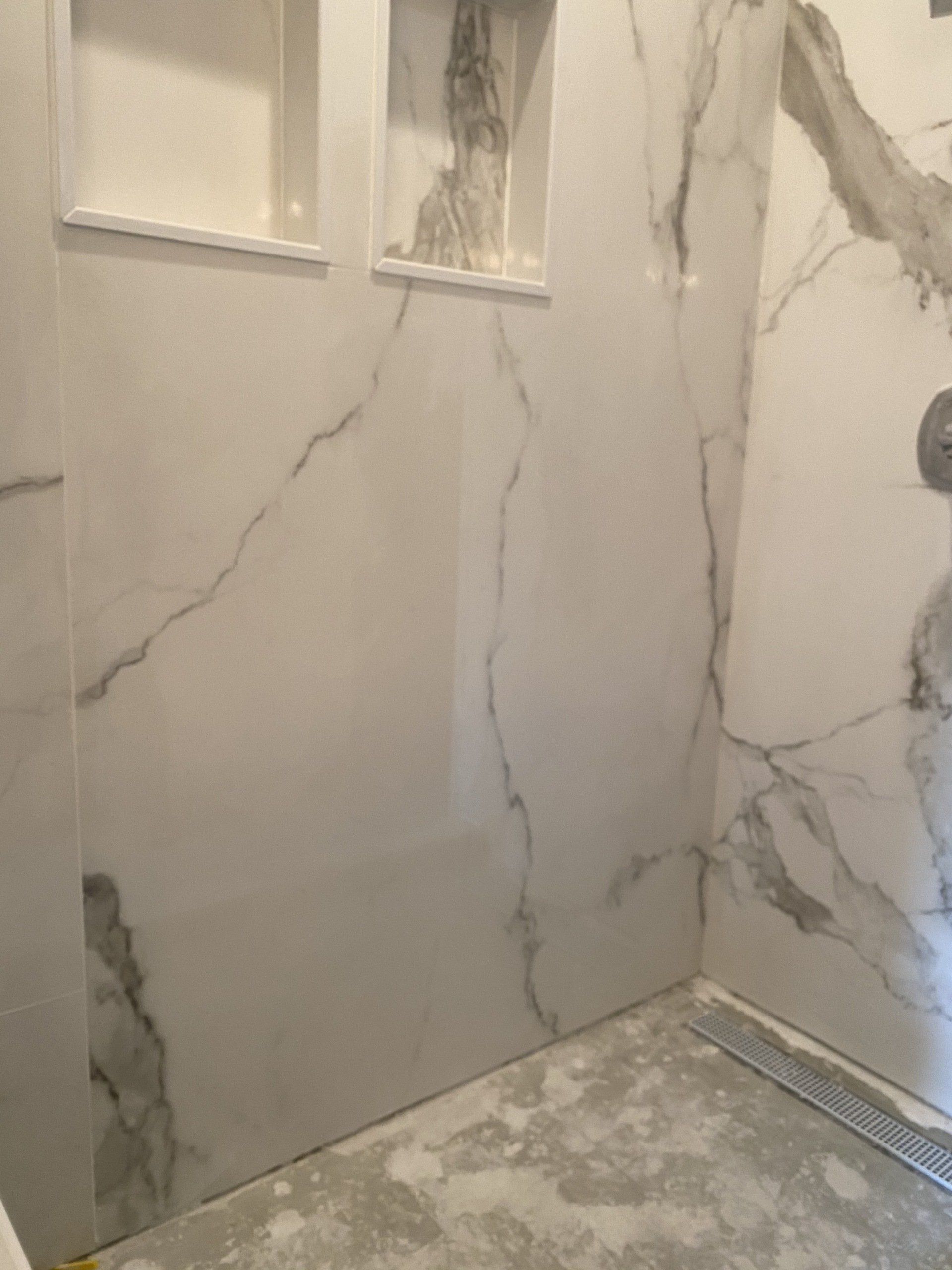 A bathroom with marble walls and a walk in shower.