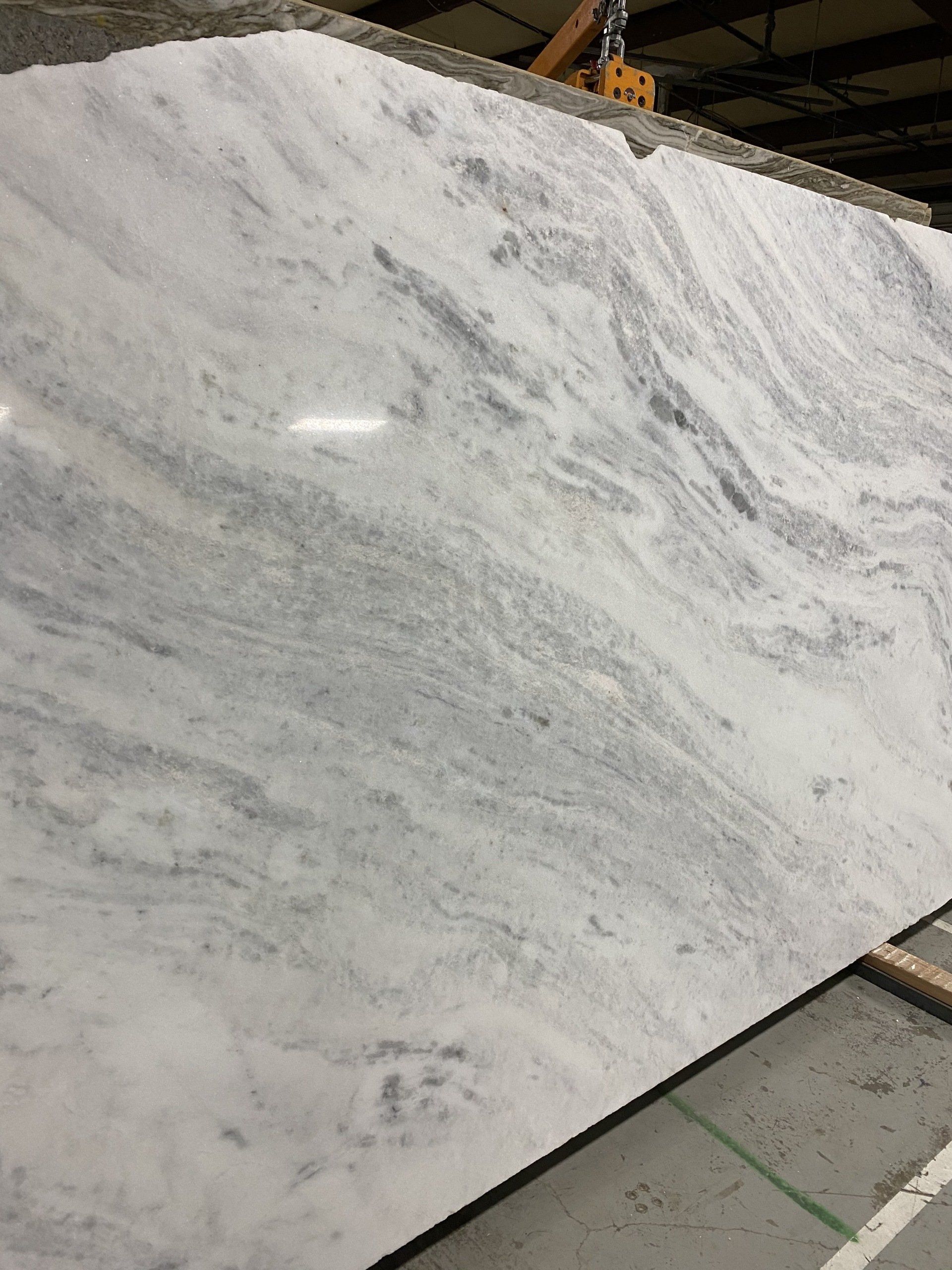 A large white marble slab is sitting on top of a cement floor.