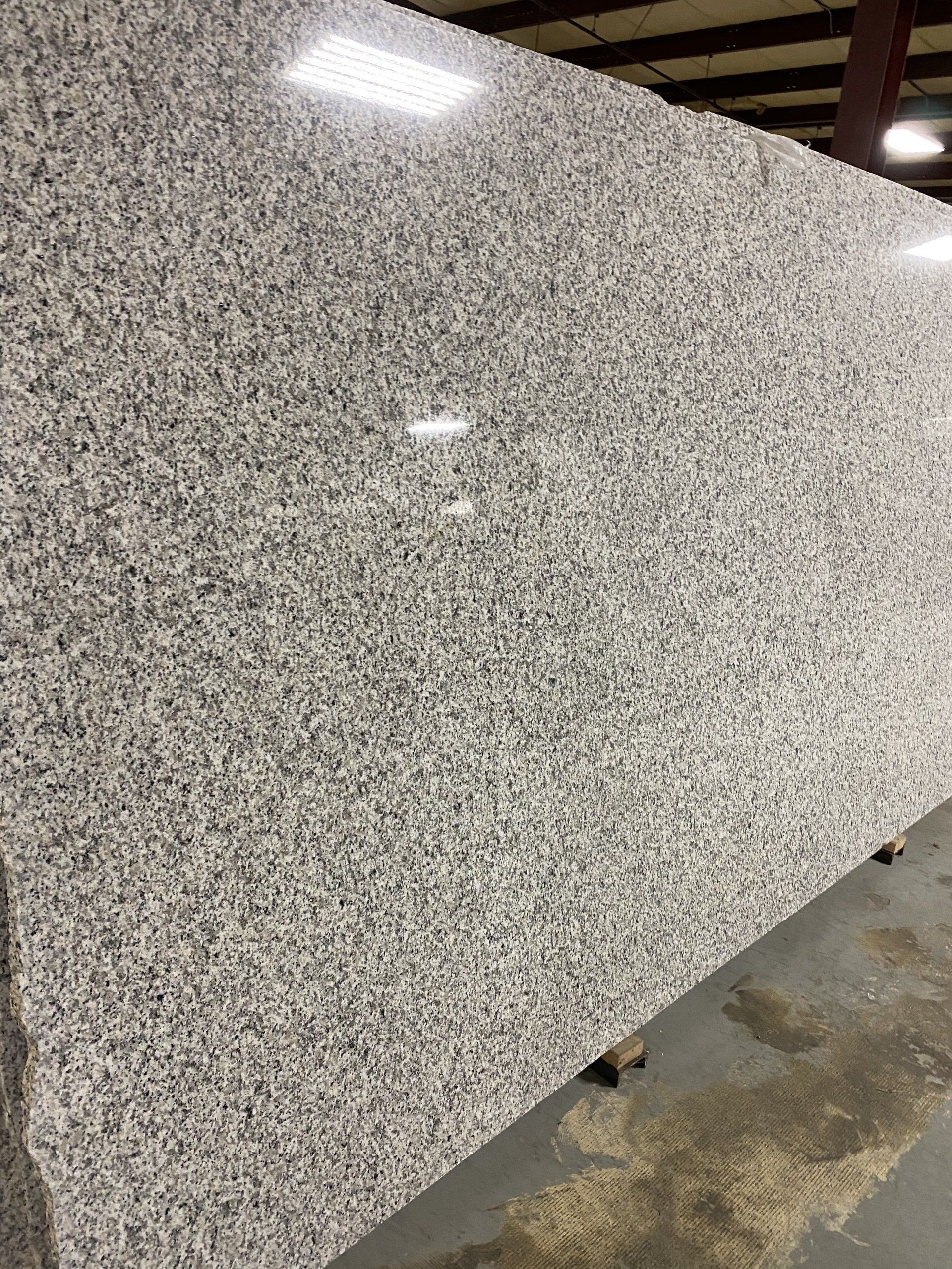 A large white granite slab is sitting on a concrete floor in a warehouse.