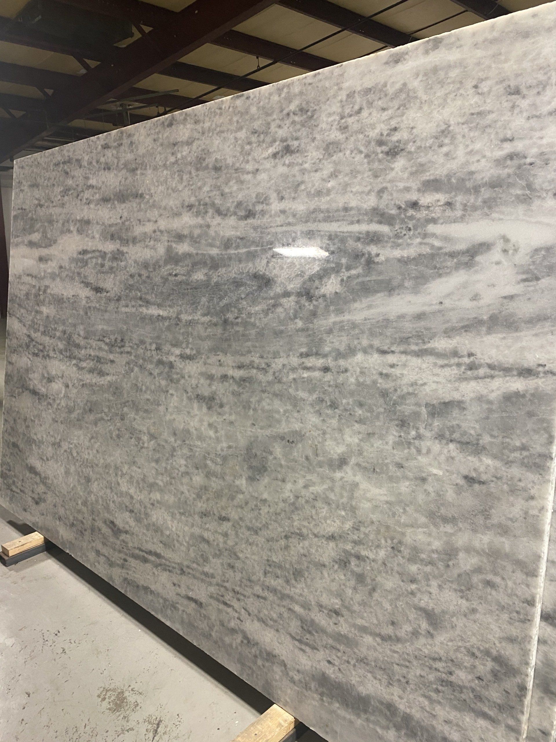 A large slab of marble is sitting on a wooden pallet in a warehouse.