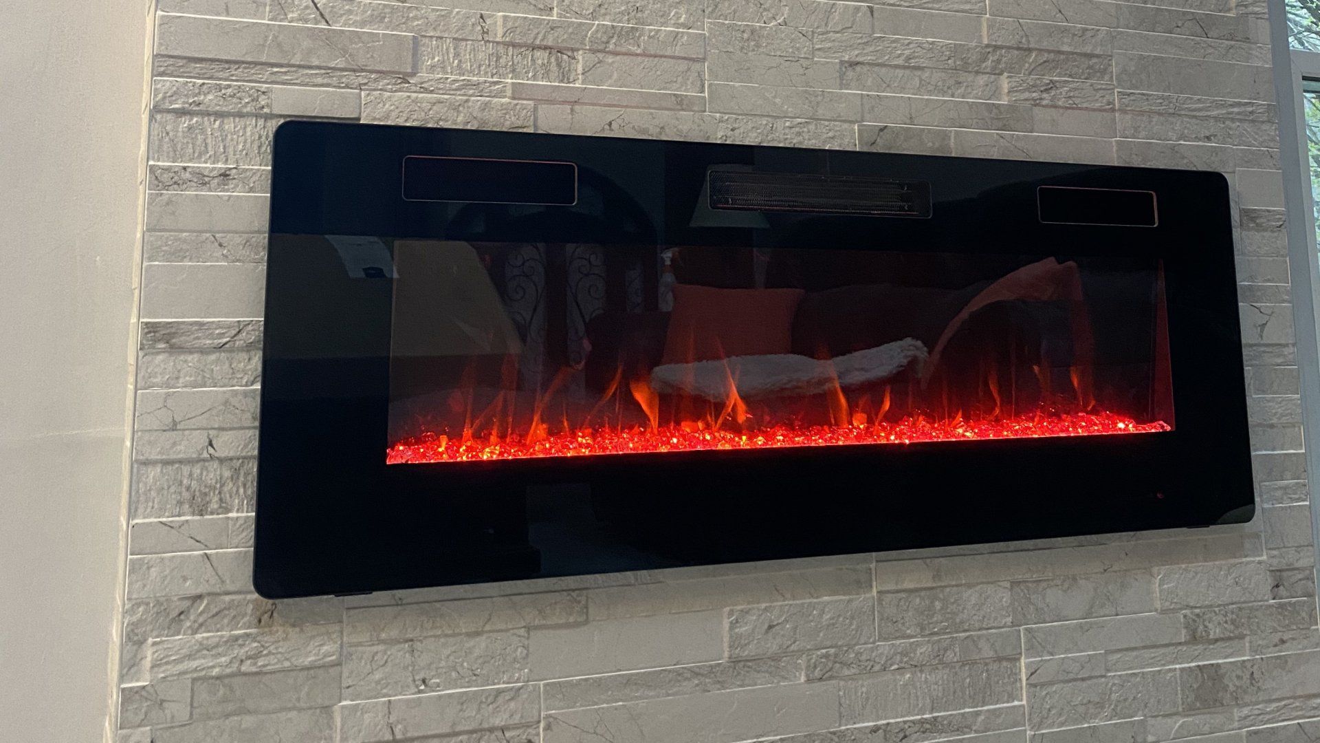 A fireplace is hanging on a brick wall in a living room.
