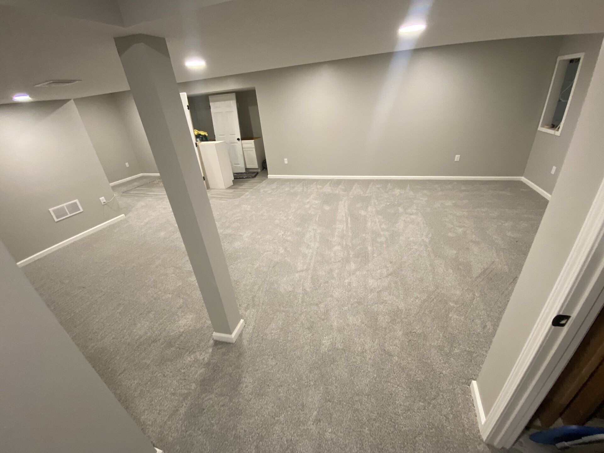 An empty basement with a gray carpet and white walls.