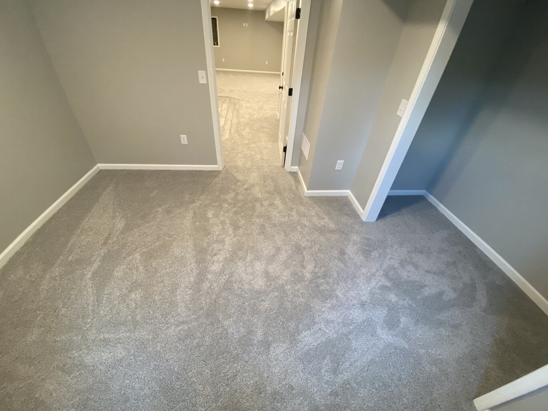 A room with a carpeted floor and a hallway leading to another room.