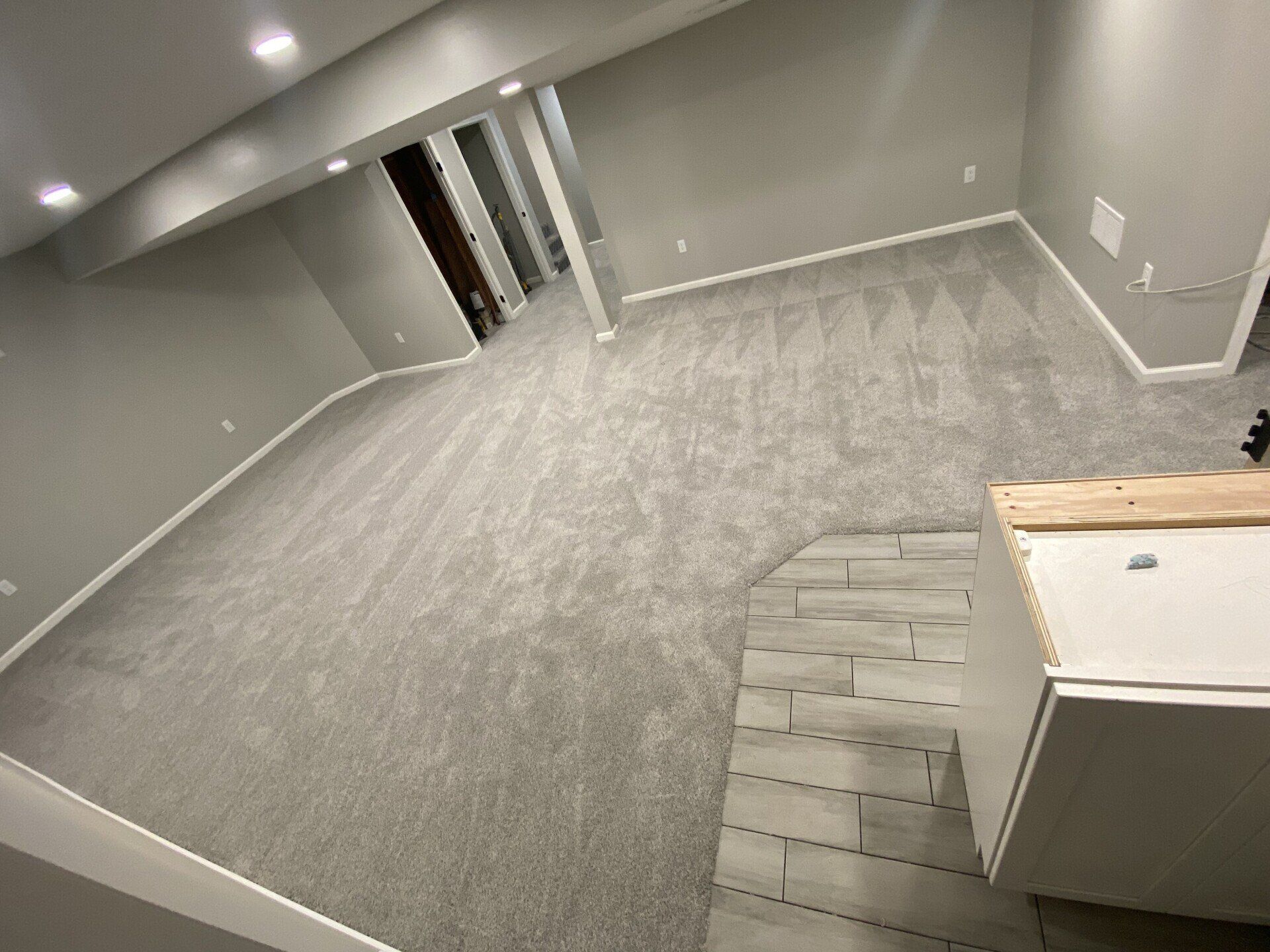 An empty basement with a carpeted floor and a sink.
