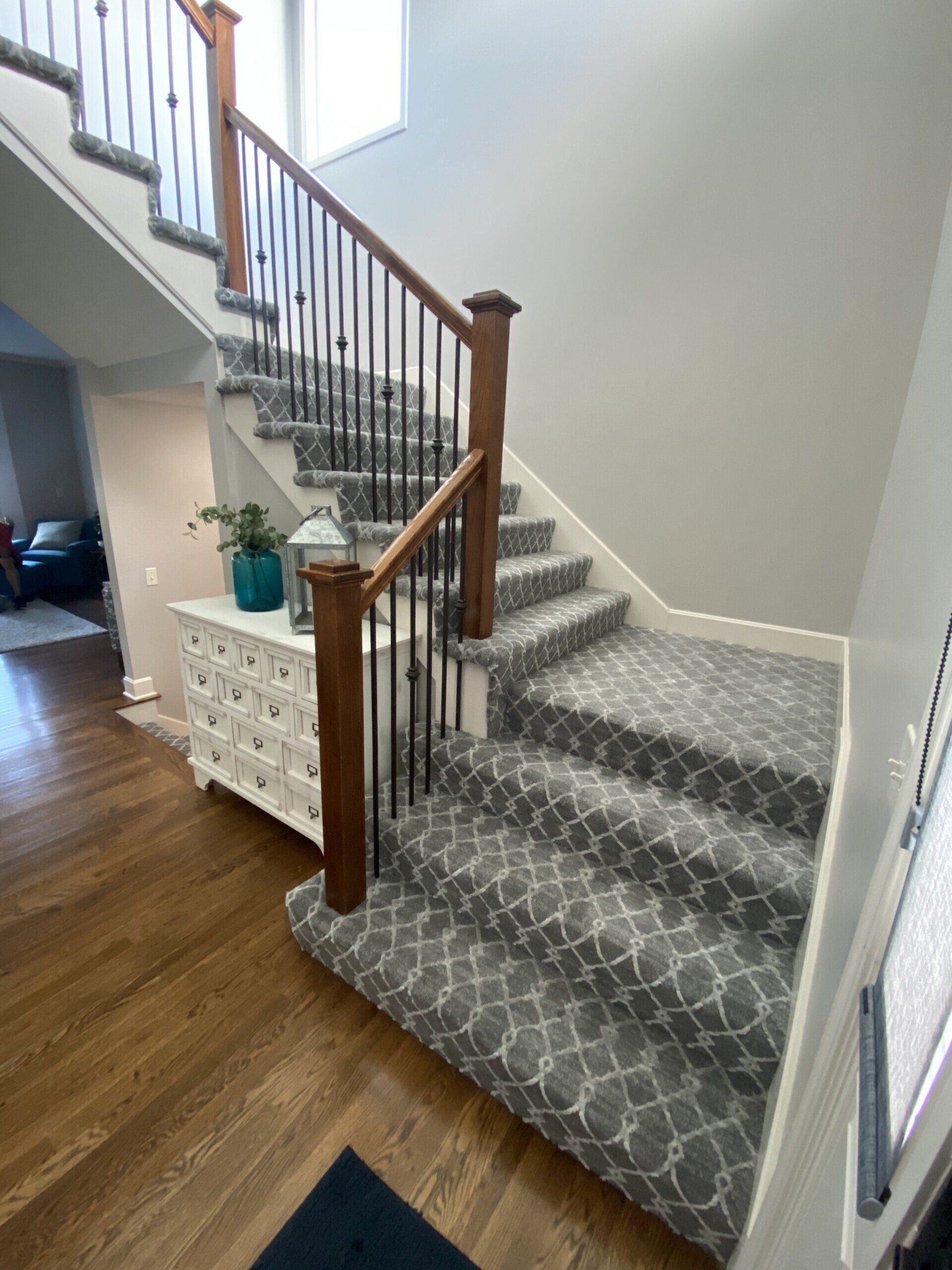 A staircase with a gray carpet and a wooden railing
