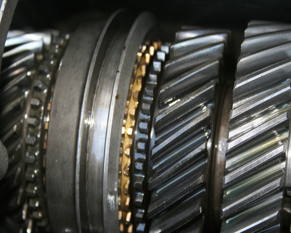 Close-up of a car's transmission gears, showing metallic components with detailed teeth and a gold-colored ring.
