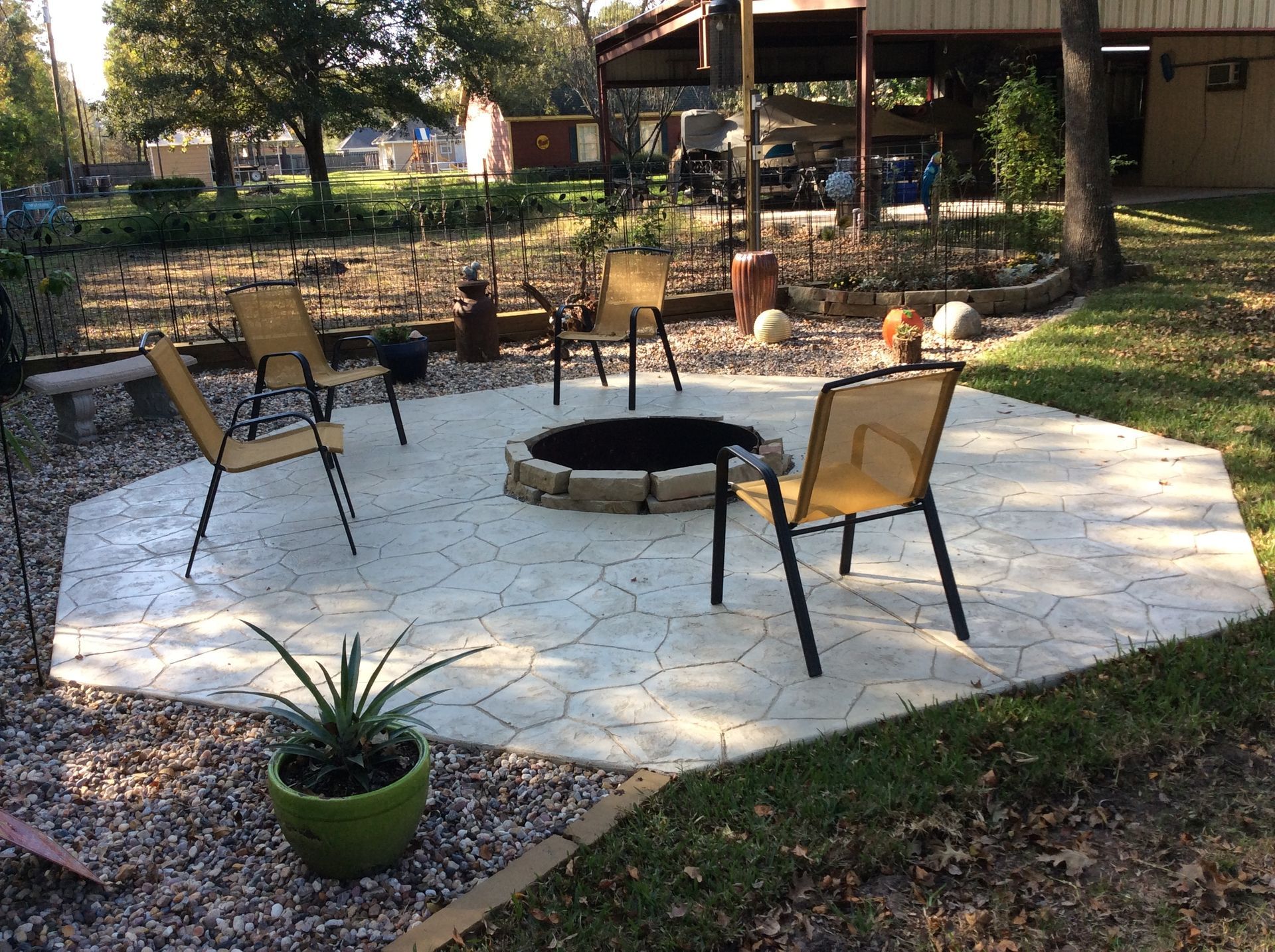 A fire pit in the middle of a patio with chairs around it.