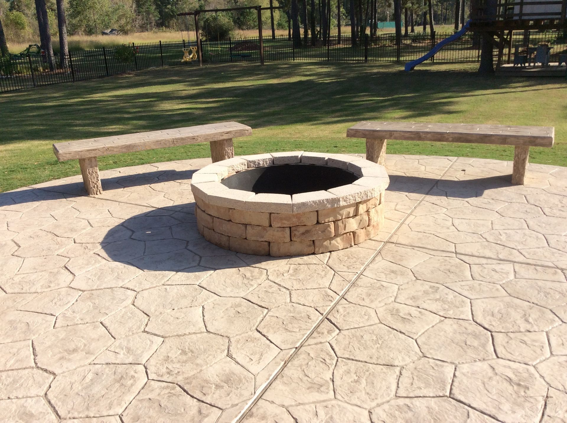 A fire pit is surrounded by benches on a patio.