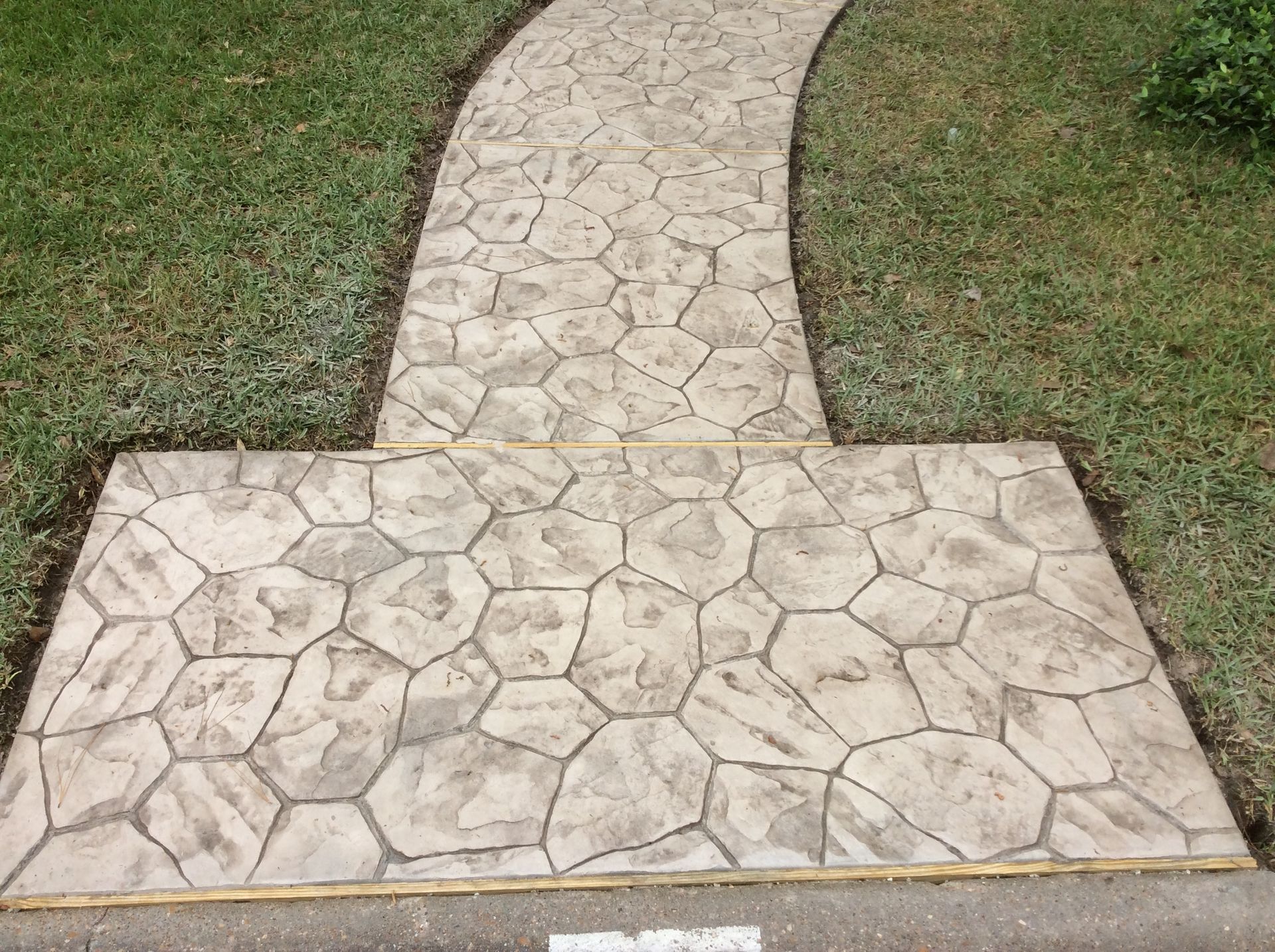 A concrete walkway going through a lush green field.