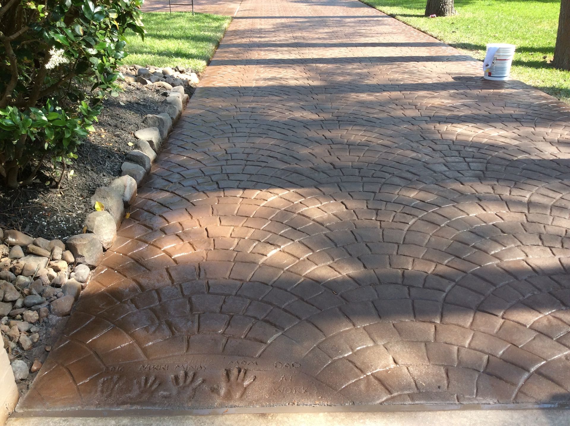 A brick walkway with a bucket on the side of it