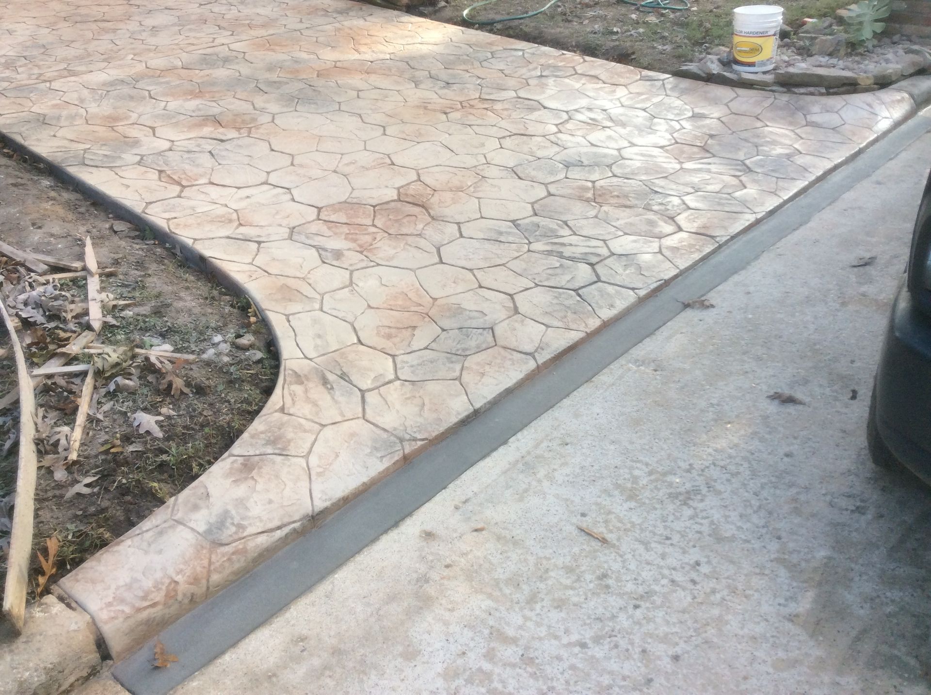 A concrete walkway with a bucket of paint in the background
