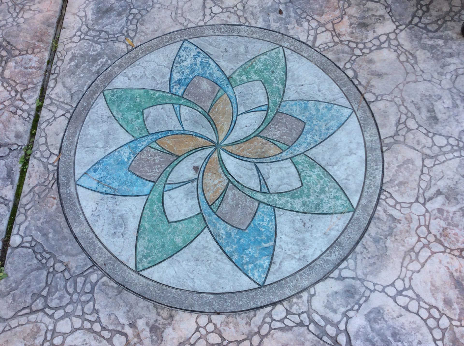 A circular pattern on a concrete floor with a flower in the center.