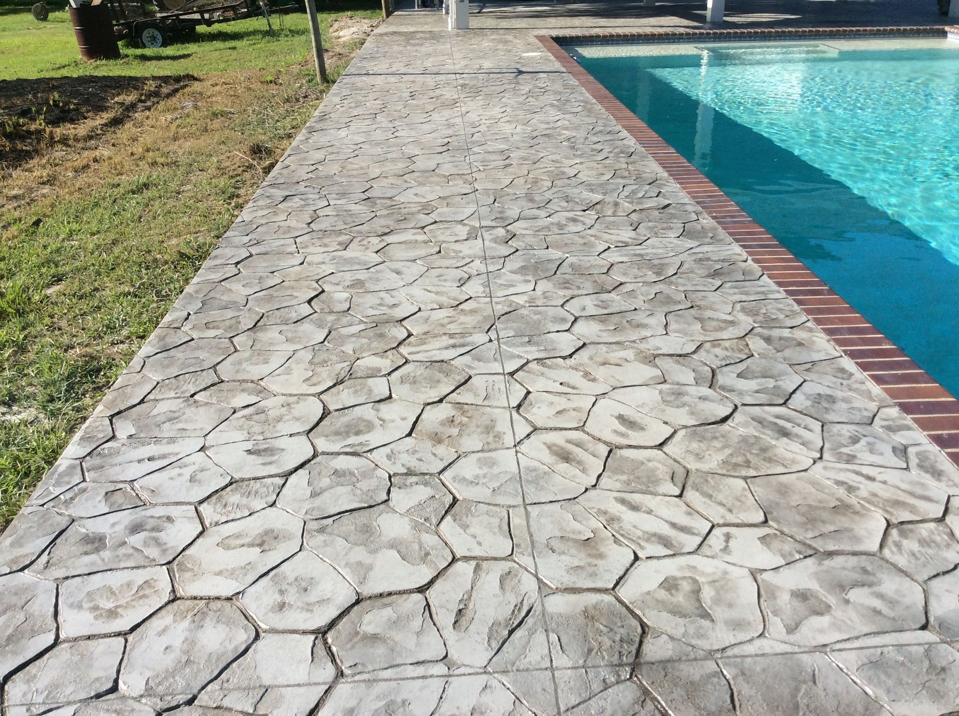 A concrete walkway leading to a swimming pool
