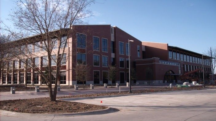 Brick building with large windows and a bare tree in front.