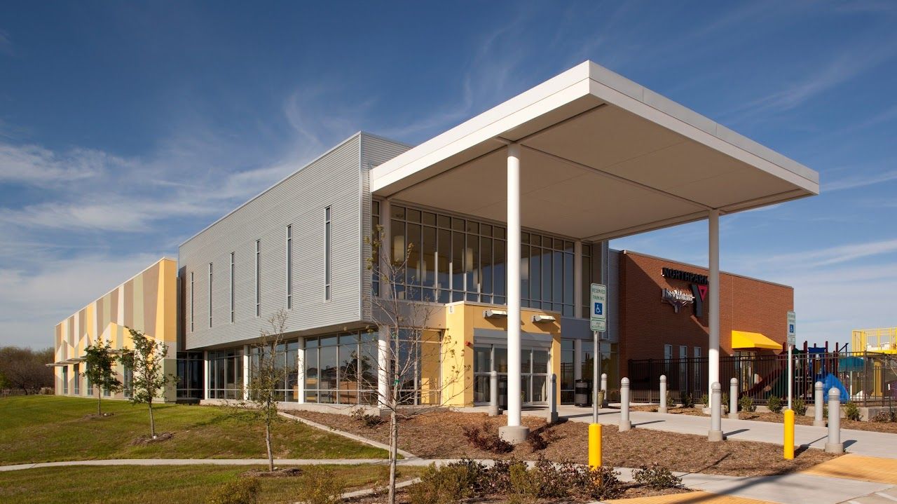 Modern building with covered entrance, accessible parking sign, and blue sky.