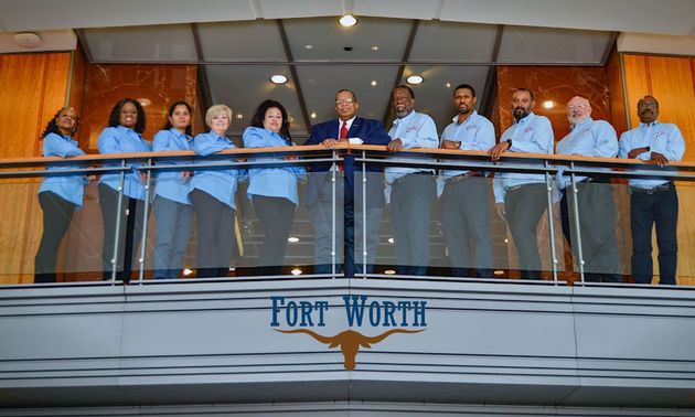 Group of people in blue shirts stand on a balcony in Fort Worth, Texas.