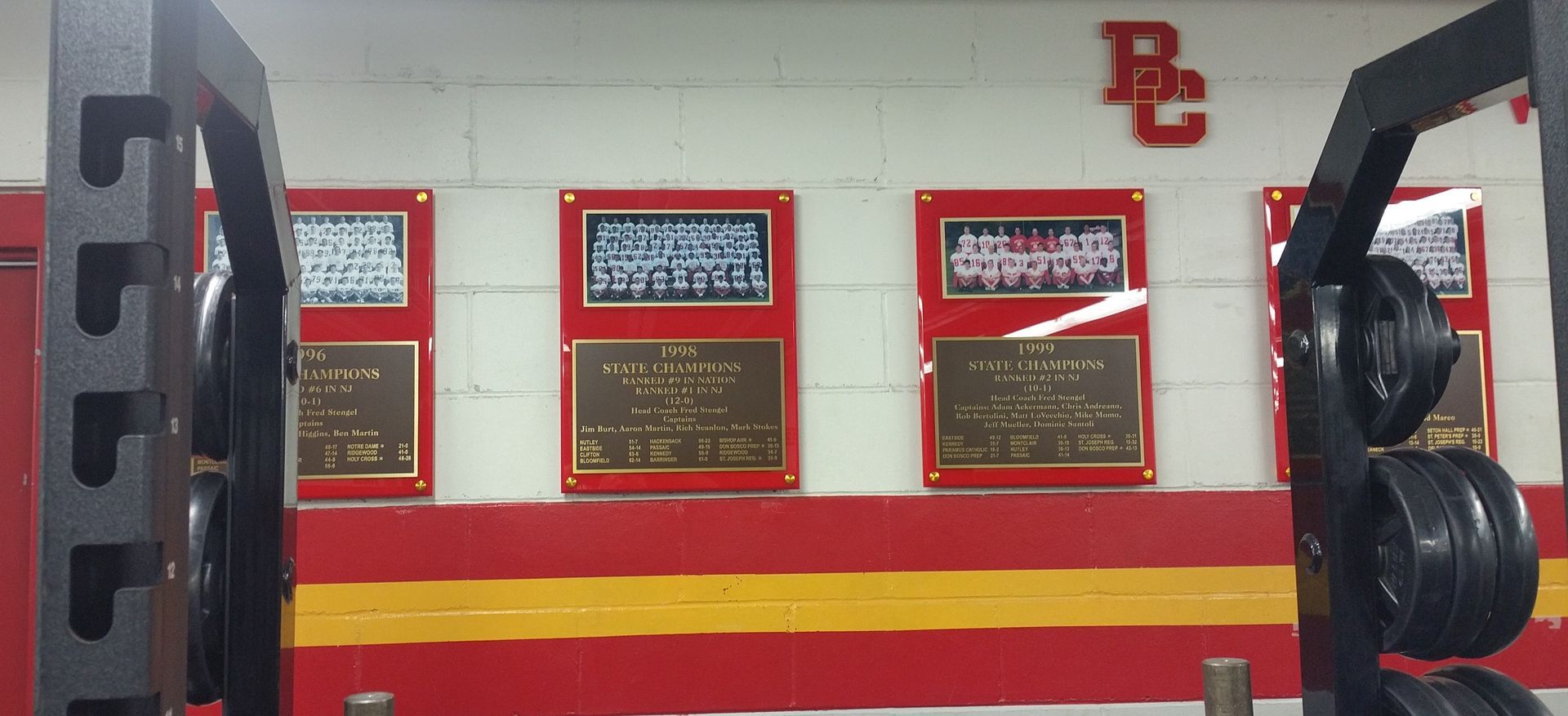 Weightlifting rack in a weight room with plaques on the wall