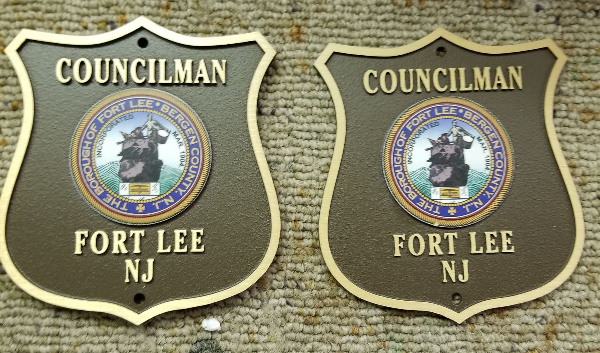 Two bronze Councilman badges from Fort Lee, NJ, with a gold border and center seal.