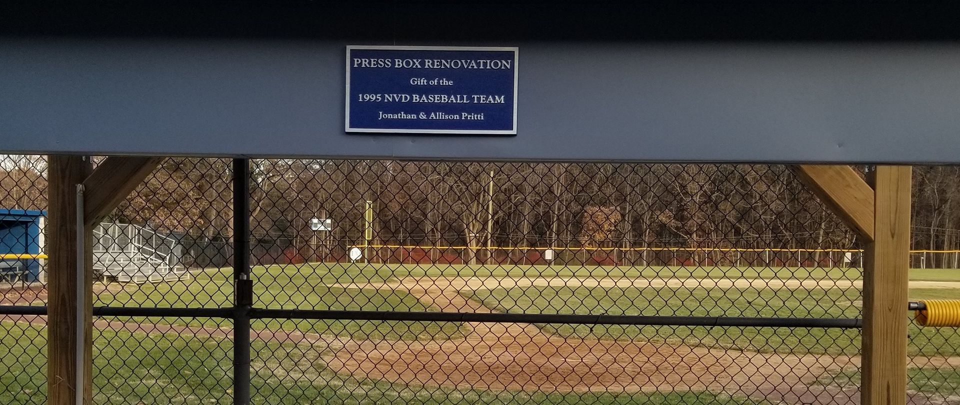 A baseball field with a chain-link fence and a sign on the dugout