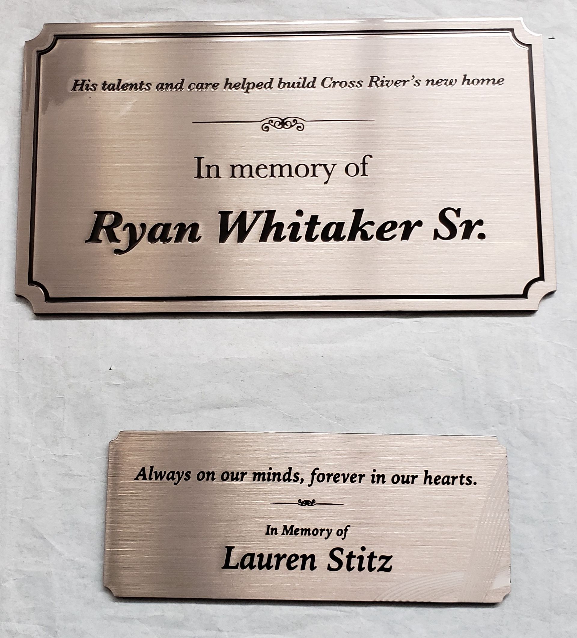 Two metal memorial plaques with text. One reads 