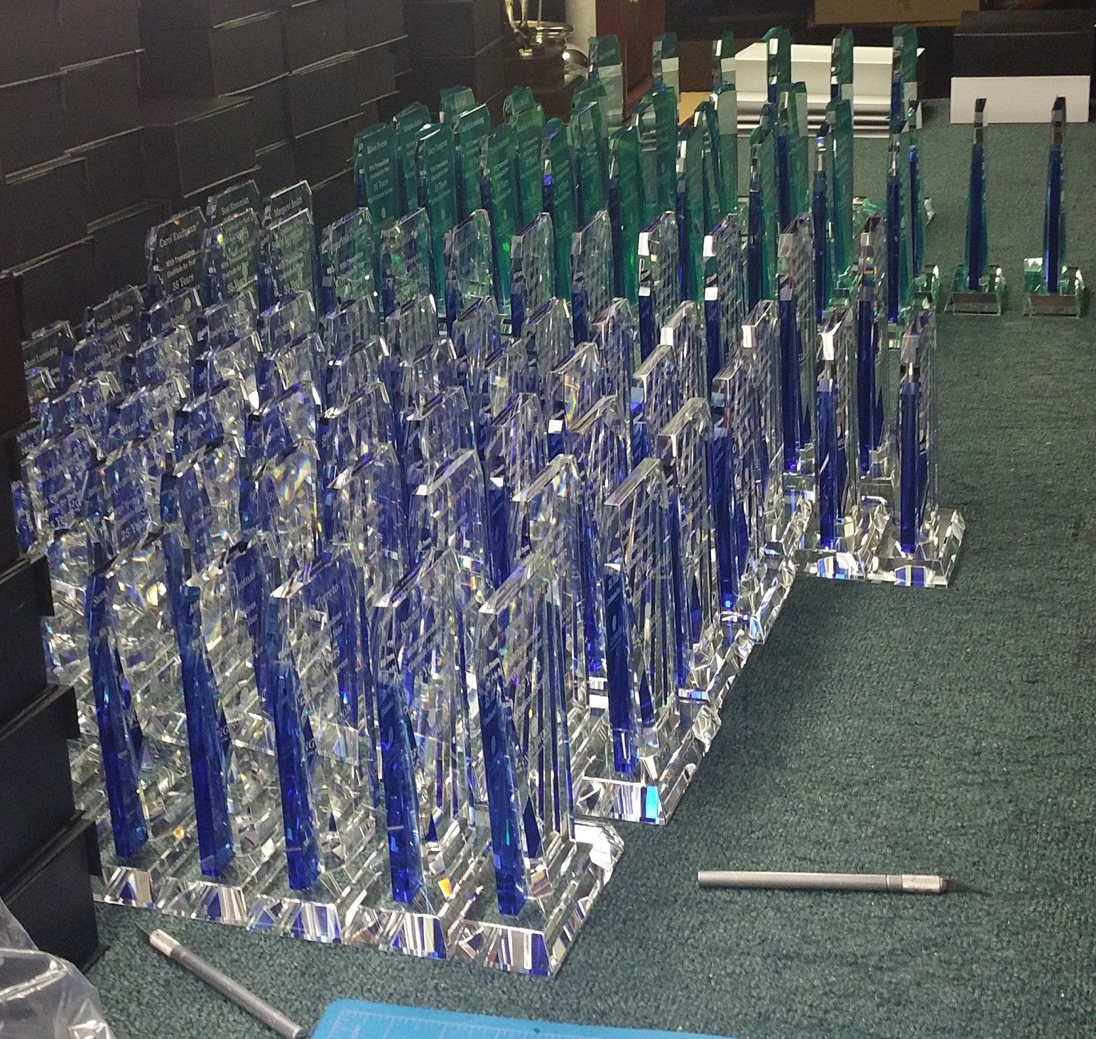 Rows of blue and green glass awards on a green surface