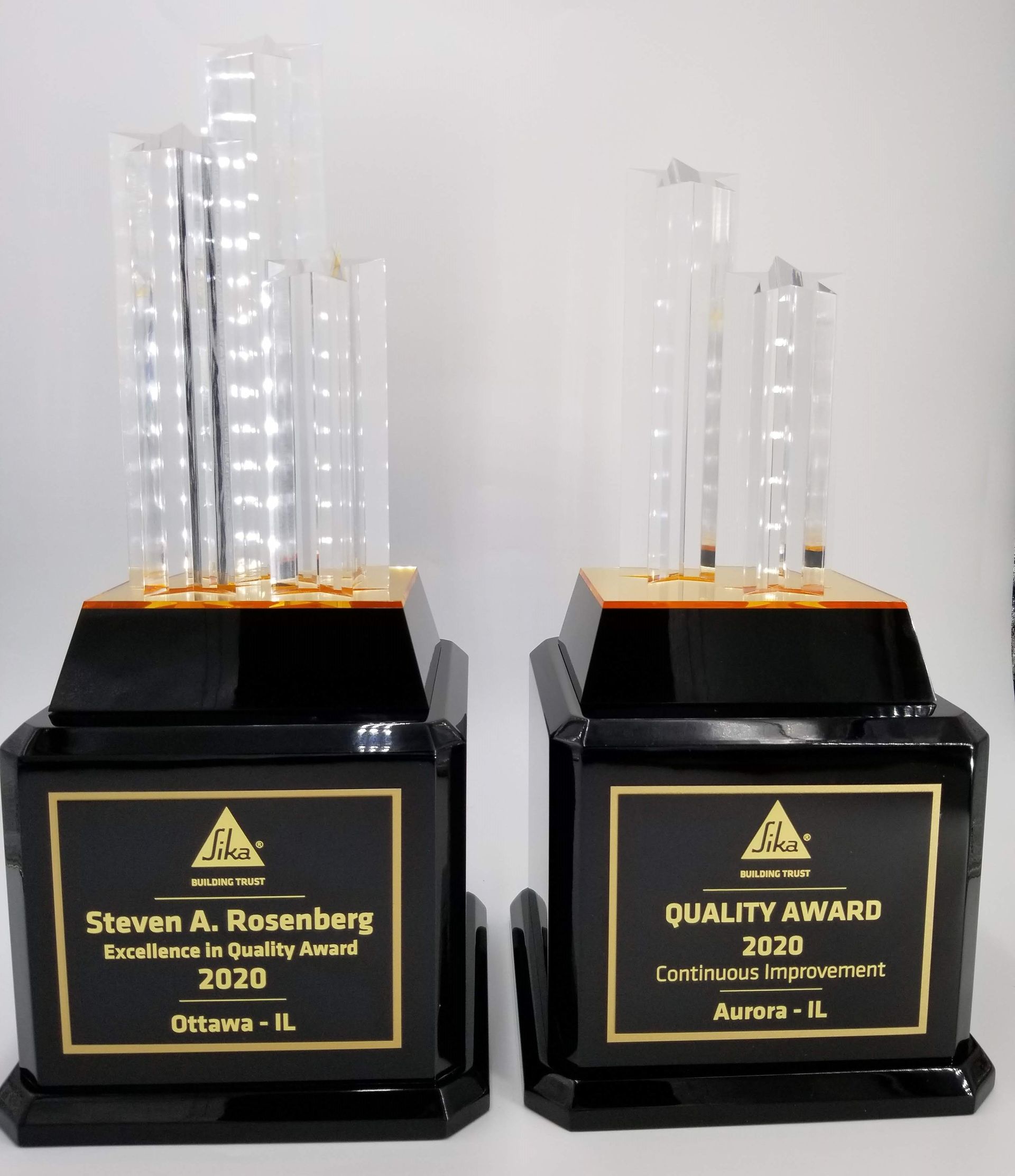 Two black and gold quality awards with clear crystal tops