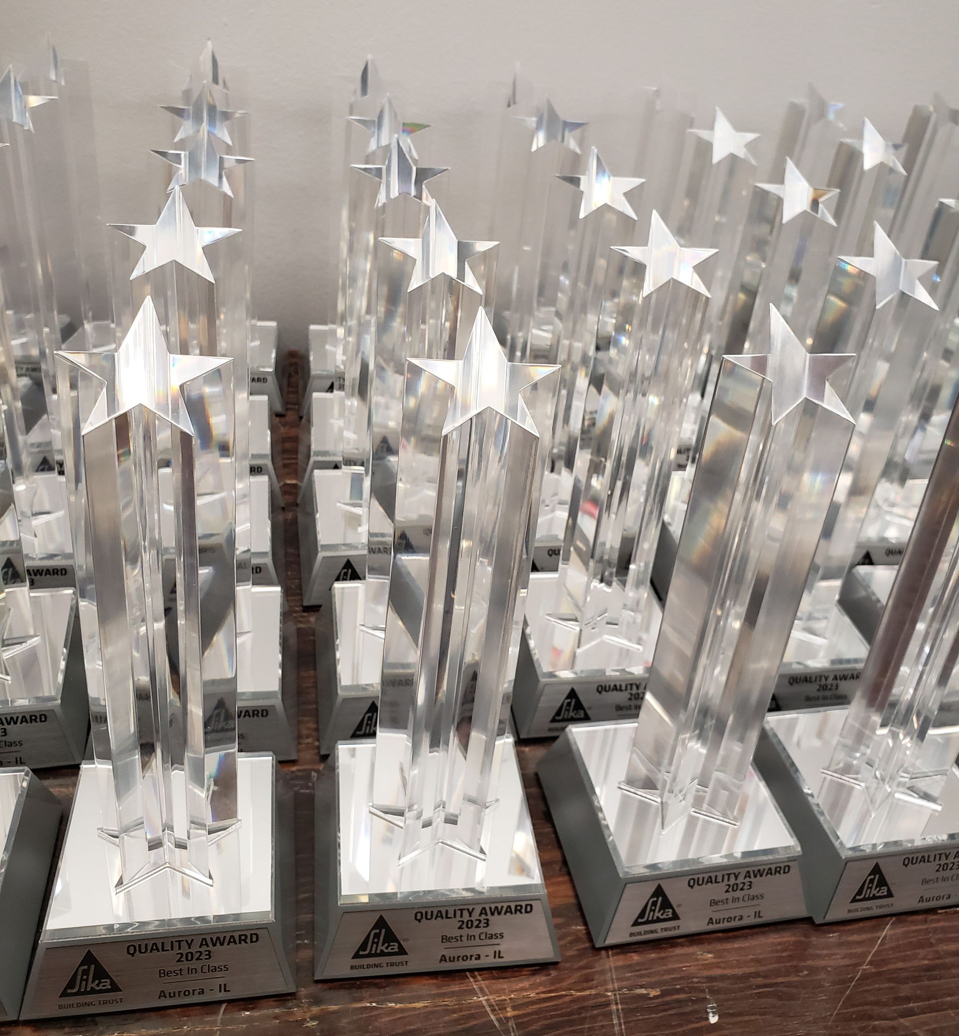 Clear star-topped trophies on silver bases, lined up on a wooden surface